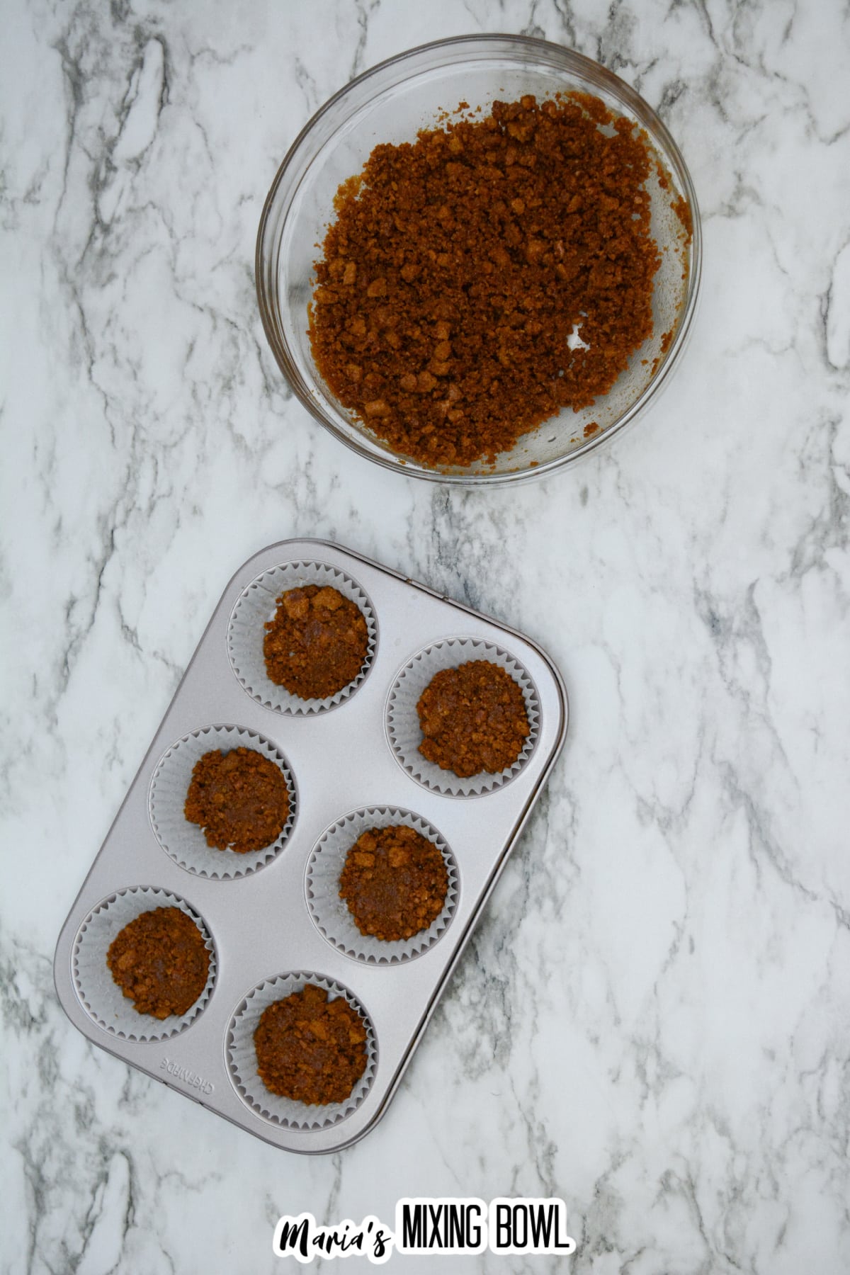 biscoff crust being pressed into a cupcake pan.
