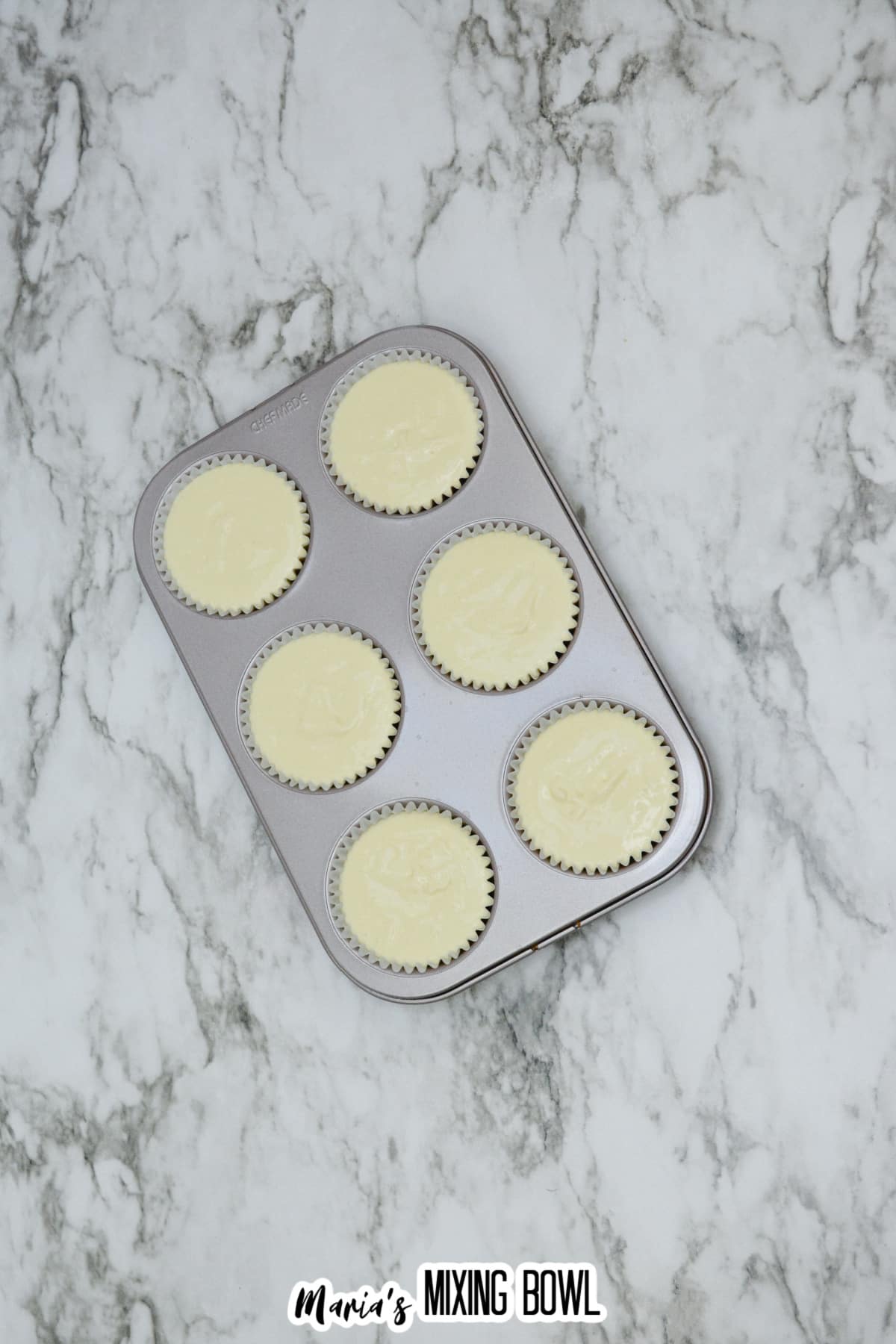 unbaked mini cheesecakes in a cupcake pan ready for the oven.