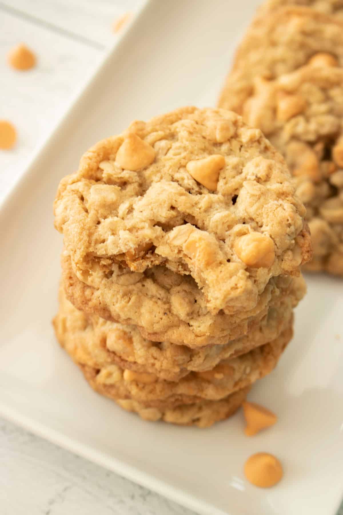 stack of four oatmeal scotchies cookies on a plate the top one has a bite missing.