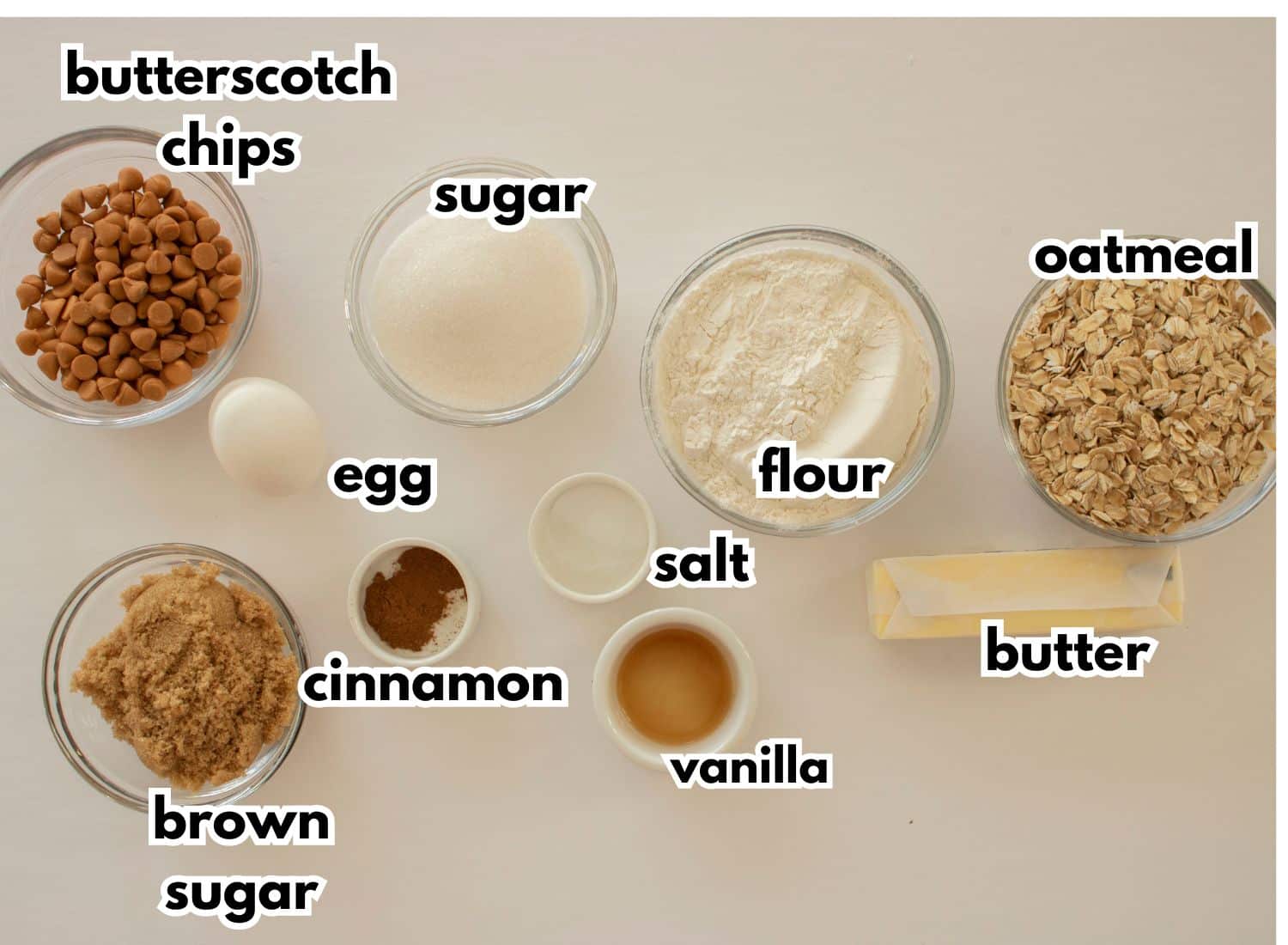 bowls of butterscotch chips, egg, sugar, flour, brown sugar, cinnamon, salt, butter, and oatmeal.