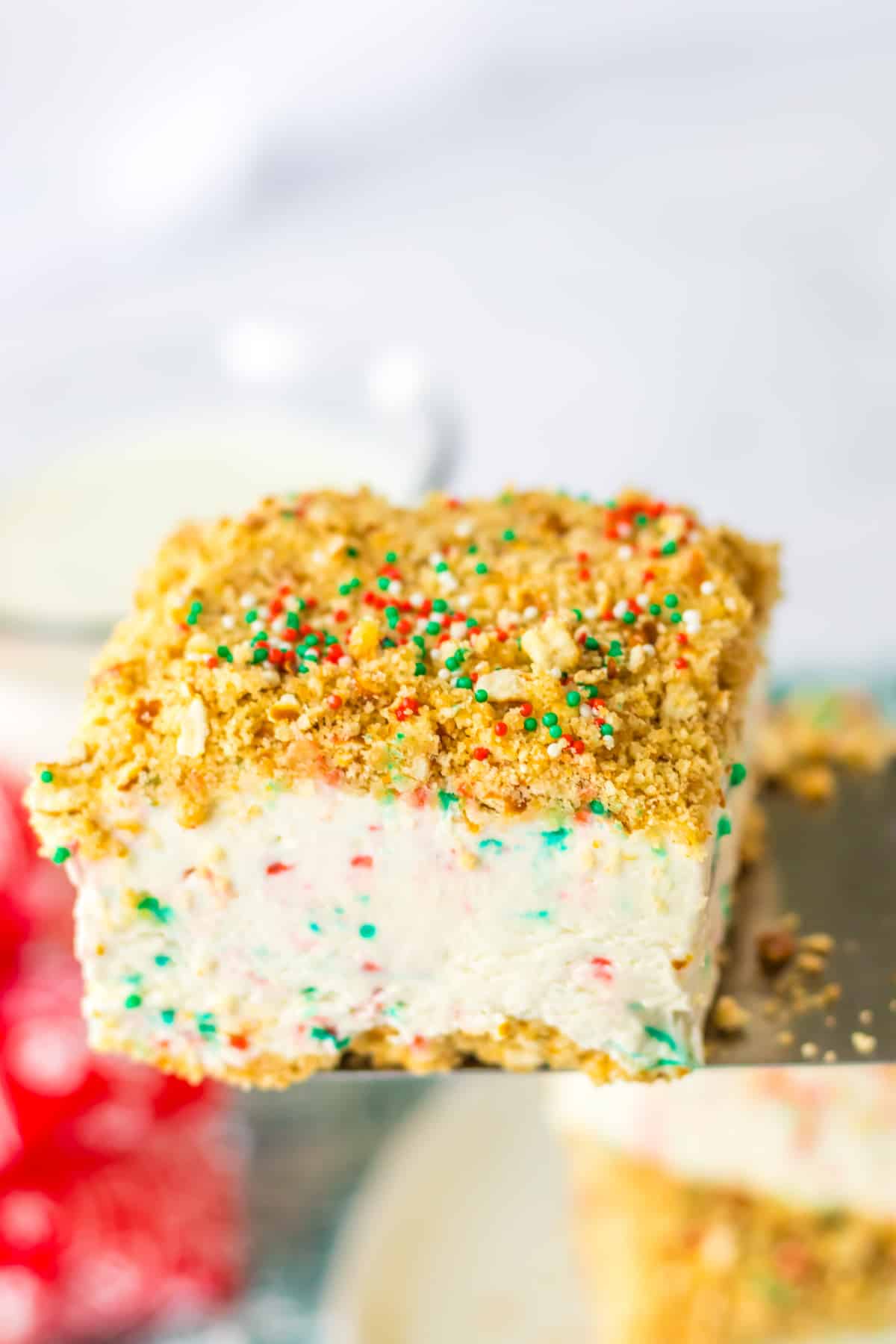 slice of peppermint crunch cake held in the air on a metal spatula.