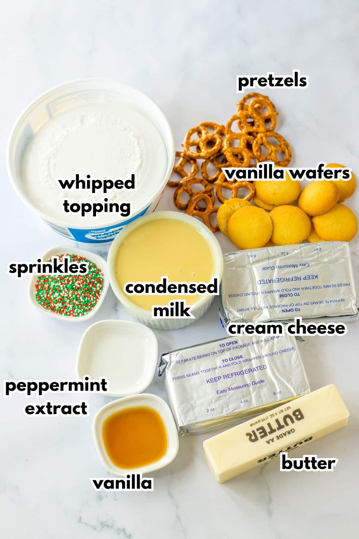 bowls of whipped topping, pretzels, vanilla wafers, sprinkles, condensed milk, peppermint extract, vanilla, butter, and cream cheese.