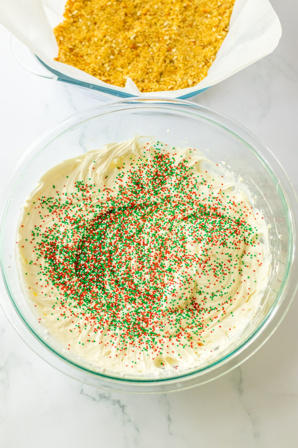 cream cheese mixture being mixed with sprinkles in a glass bowl.