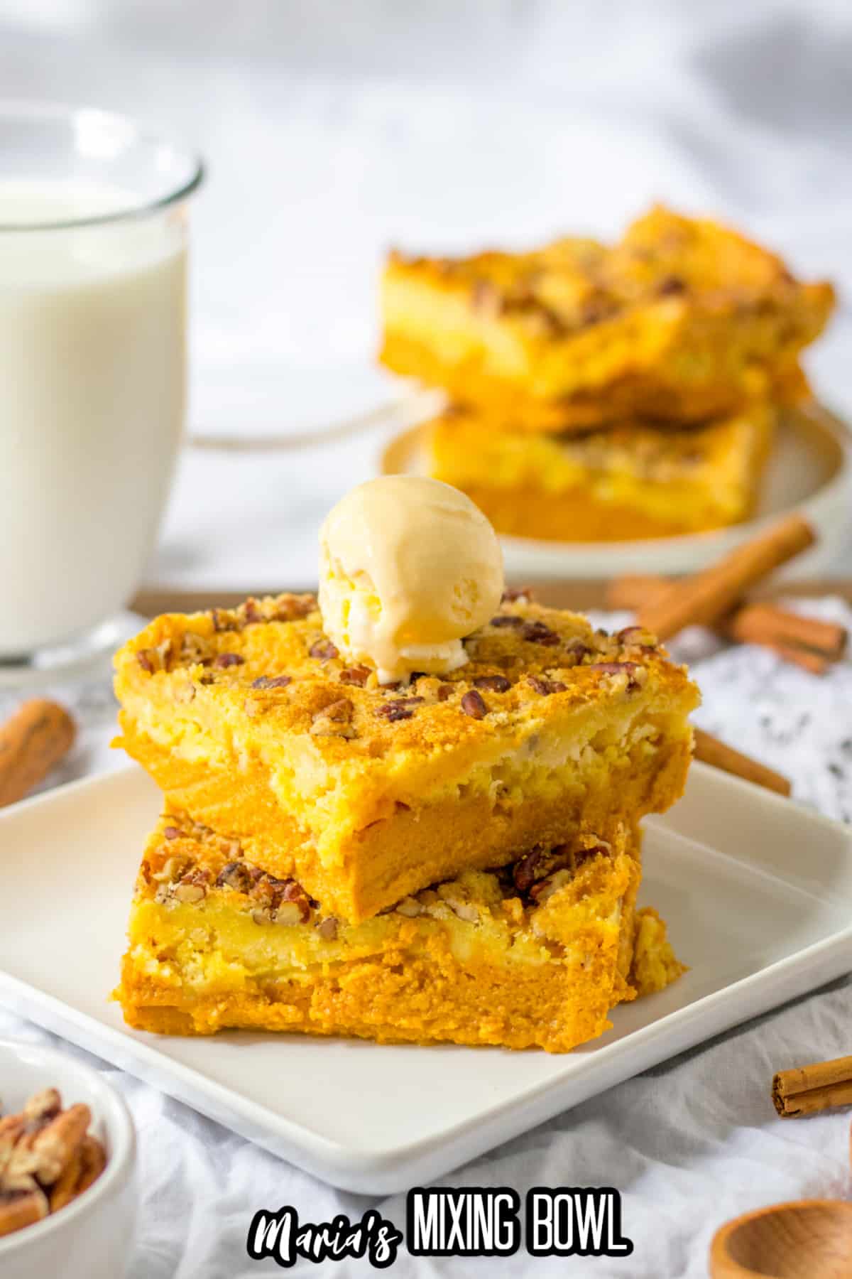 two slices of pumpkin crunch dump cake stacked on a plate with a scoop of ice cream on top.