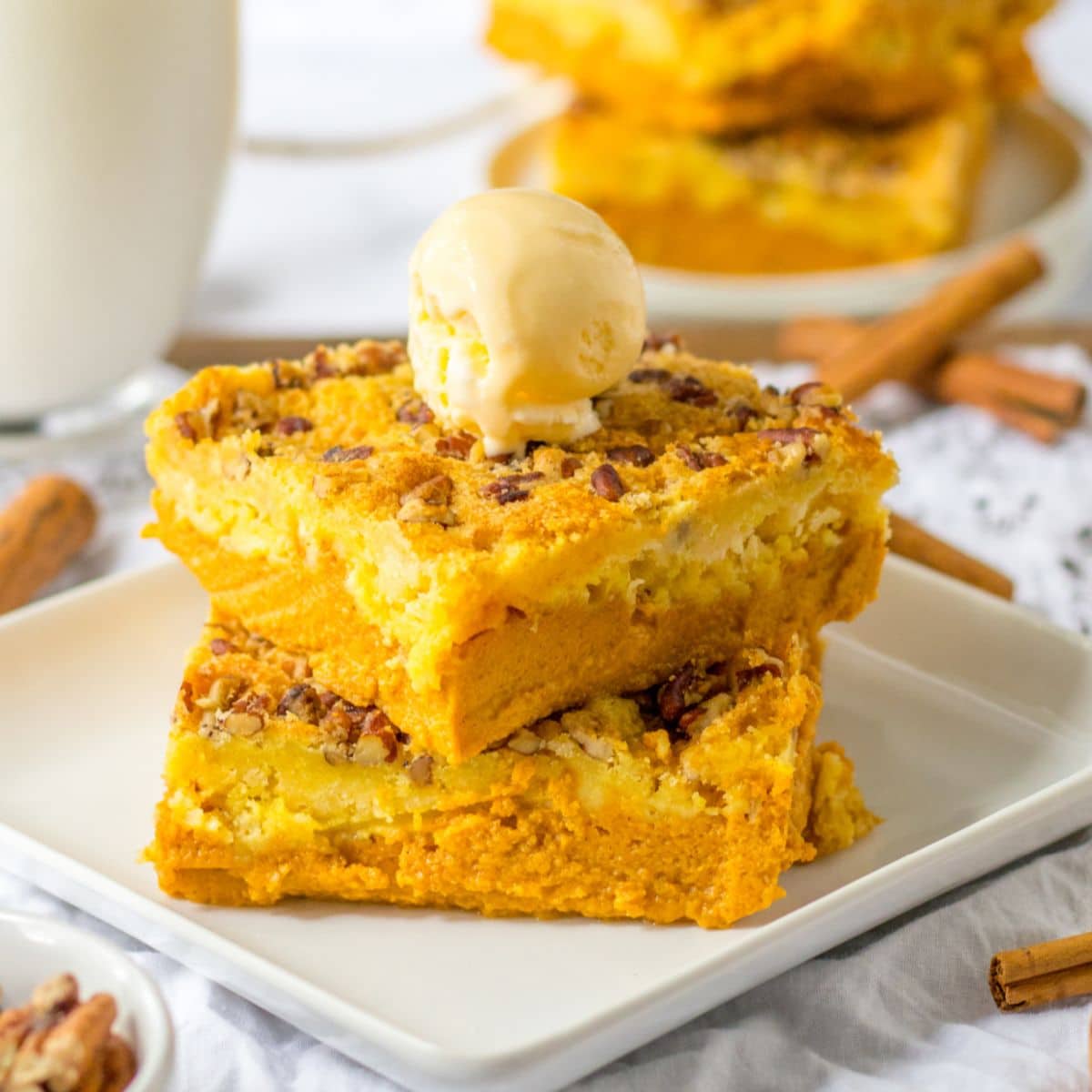two slices of pumpkin crunch dump cake stacked on a plate with a scoop of ice cream on top.
