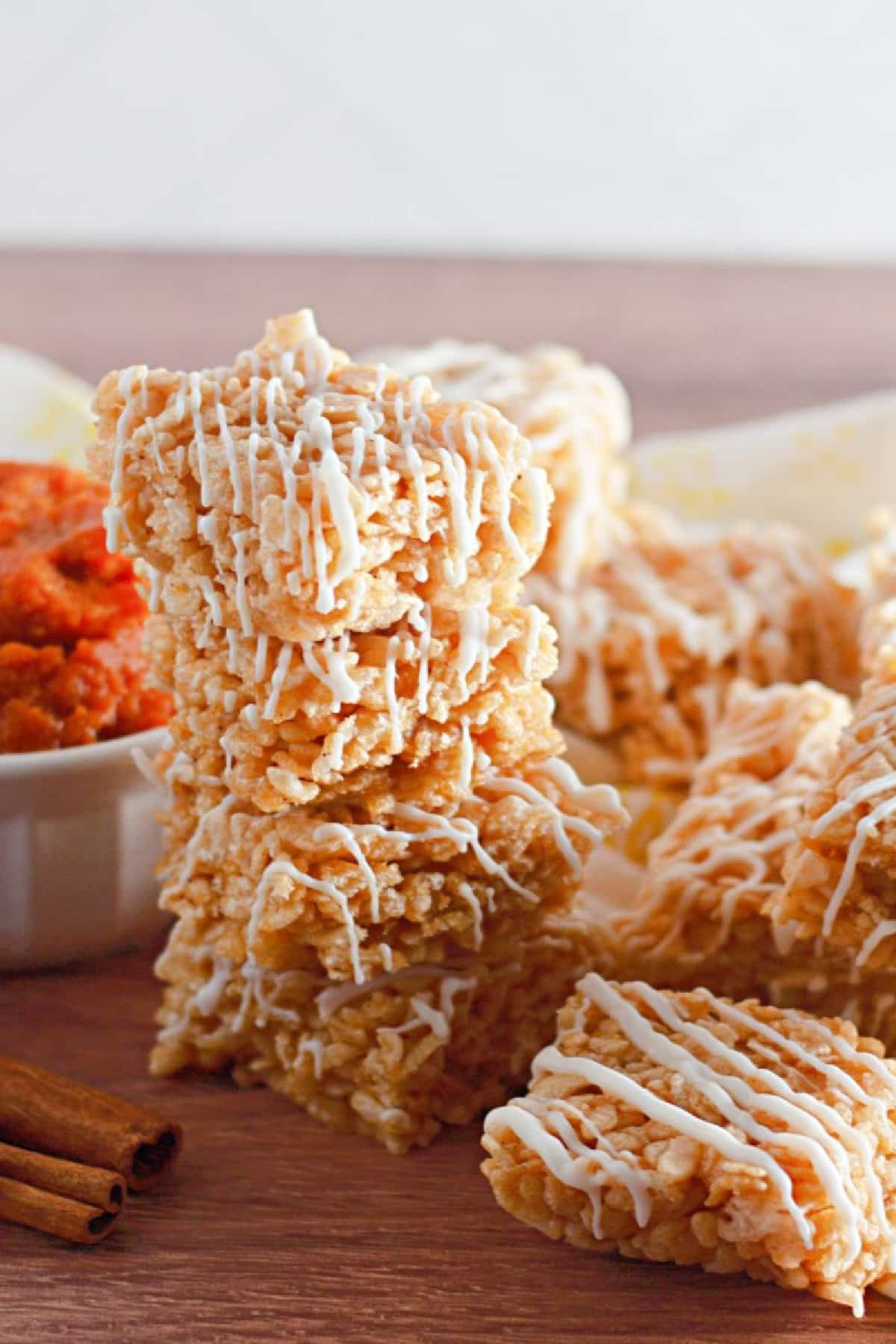 stack of pumpkin spice rice krispies treats on a wooden cutting board.