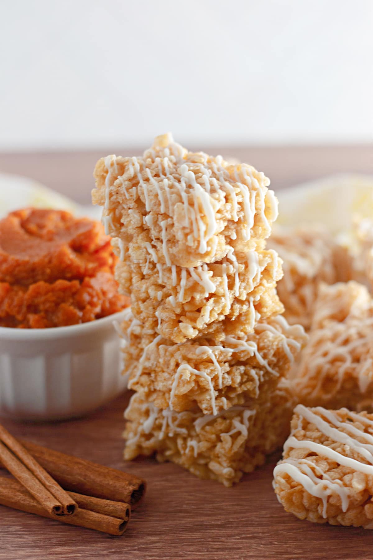 stack of pumpkin spice rice krispies treats on a wooden cutting board.