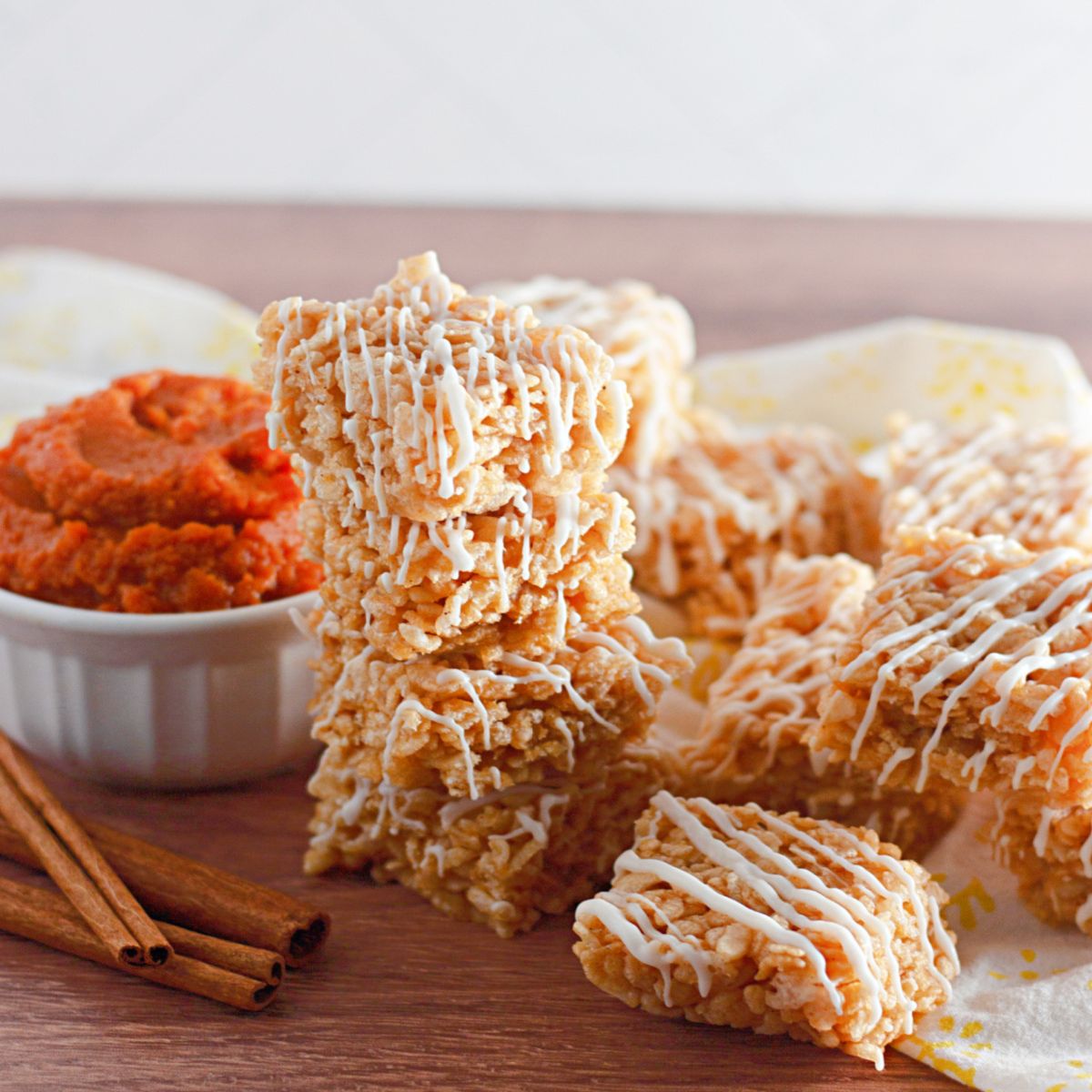 stack of pumpkin spice rice krispies treats on a wooden cutting board.