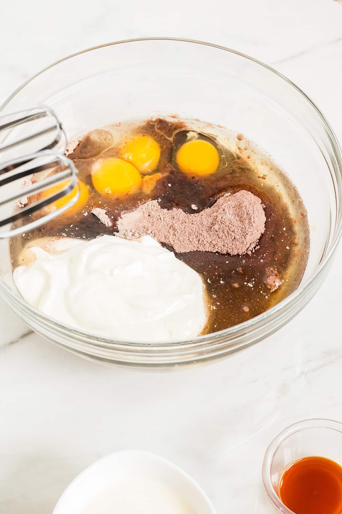 cake batter, eggs, oil, and sour cream in a glass mixing bowl.