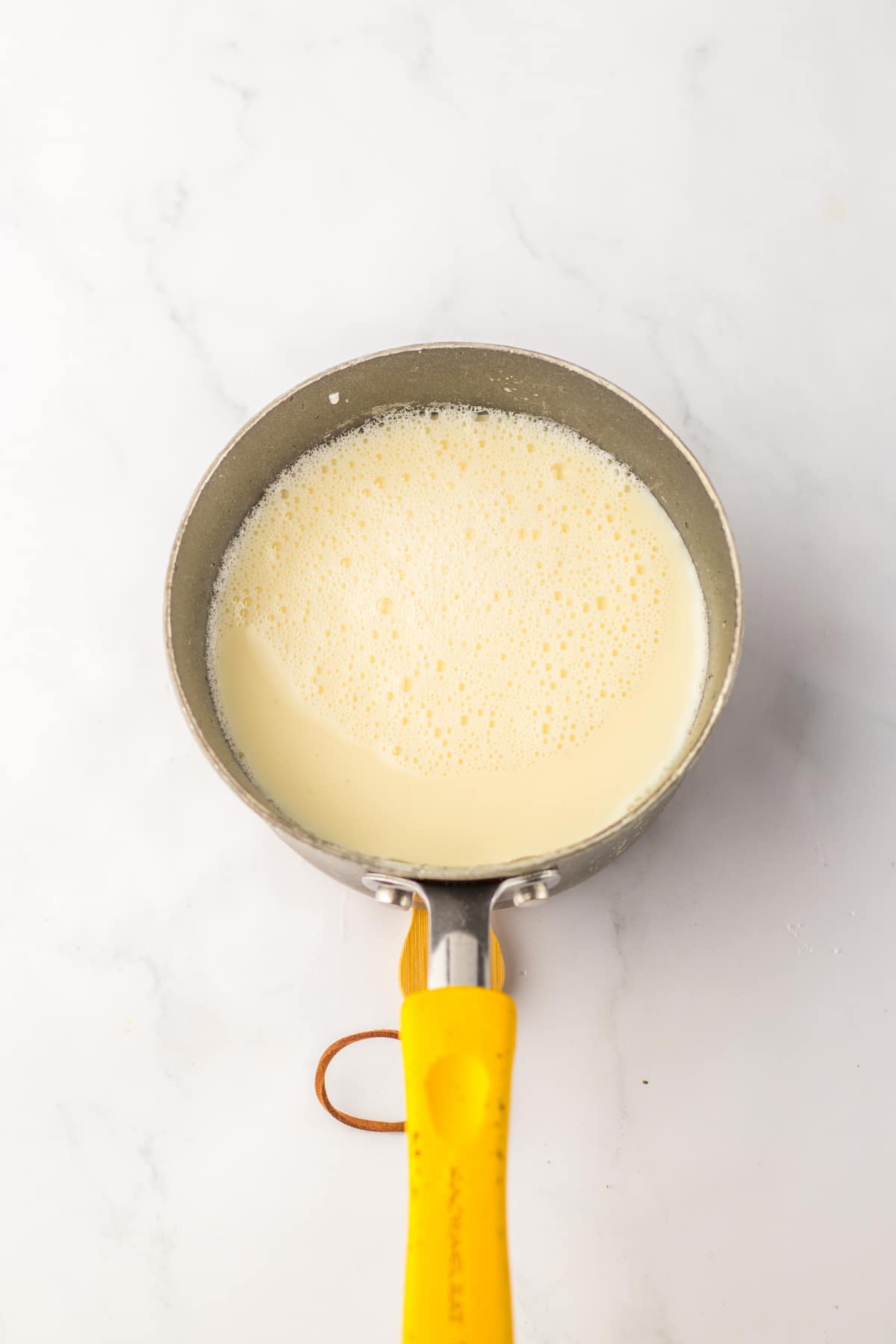 sweetened condensed milk being heated in a saucepan.