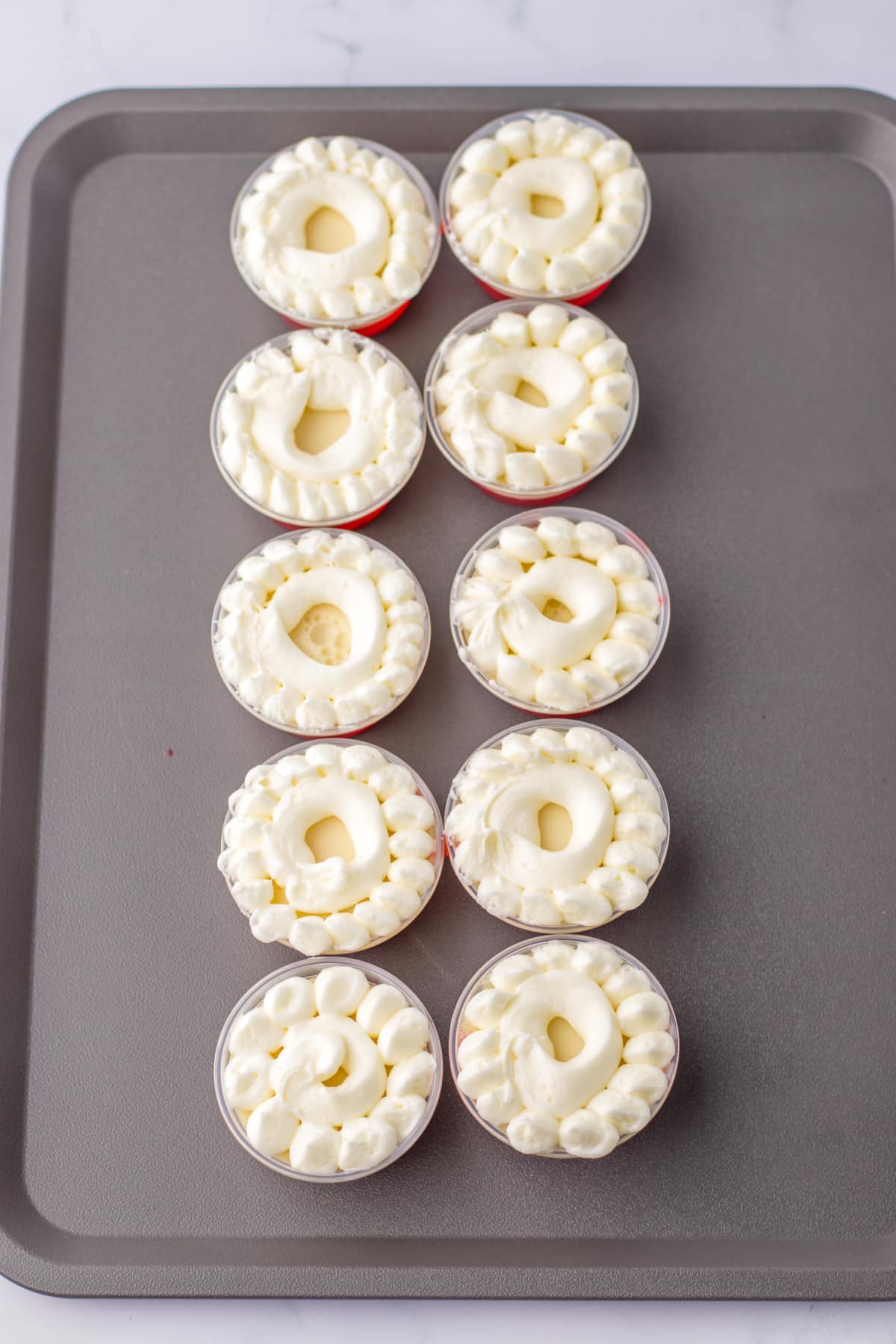 buttercream frosting being piped on top of jello shots.