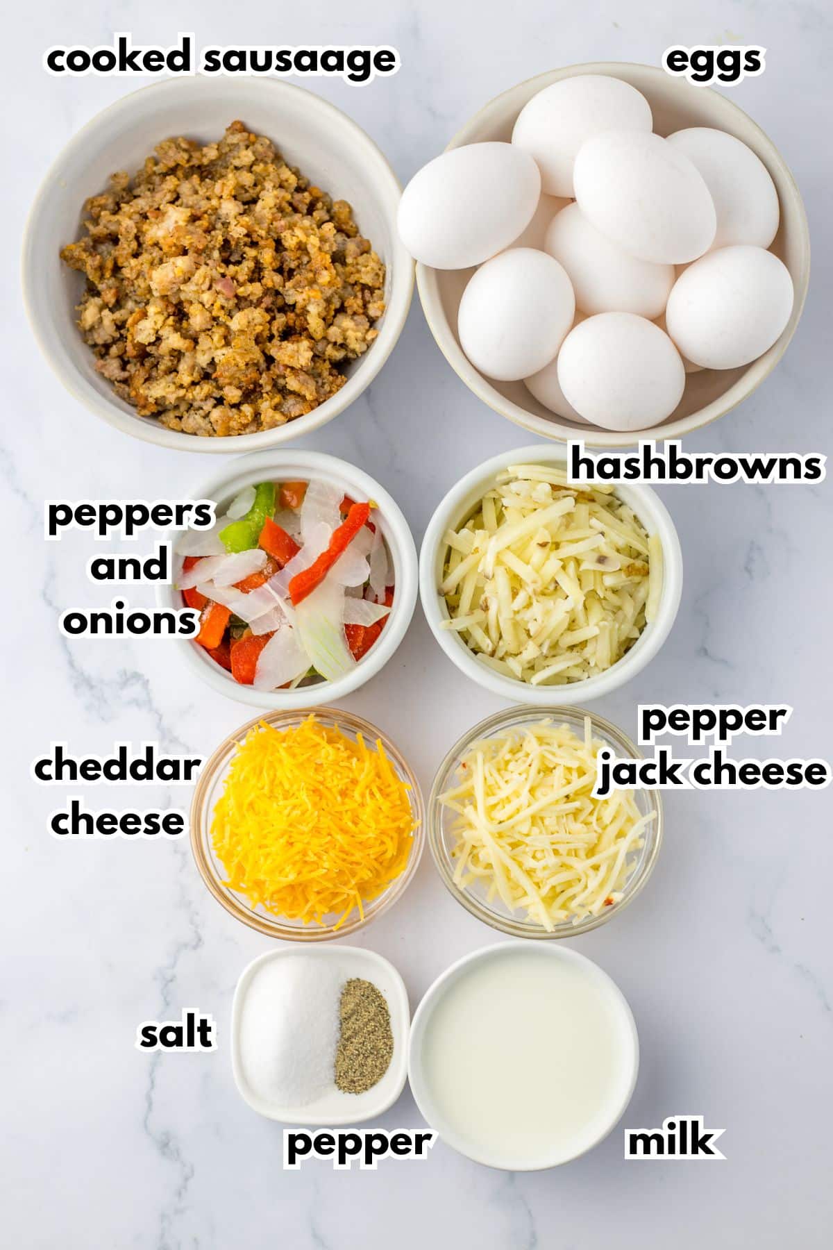 bowls of cooked sausage, eggs, peppers and onions, hashbrowns, cheddar cheese, pepper jack cheese, salt, pepper and milk.