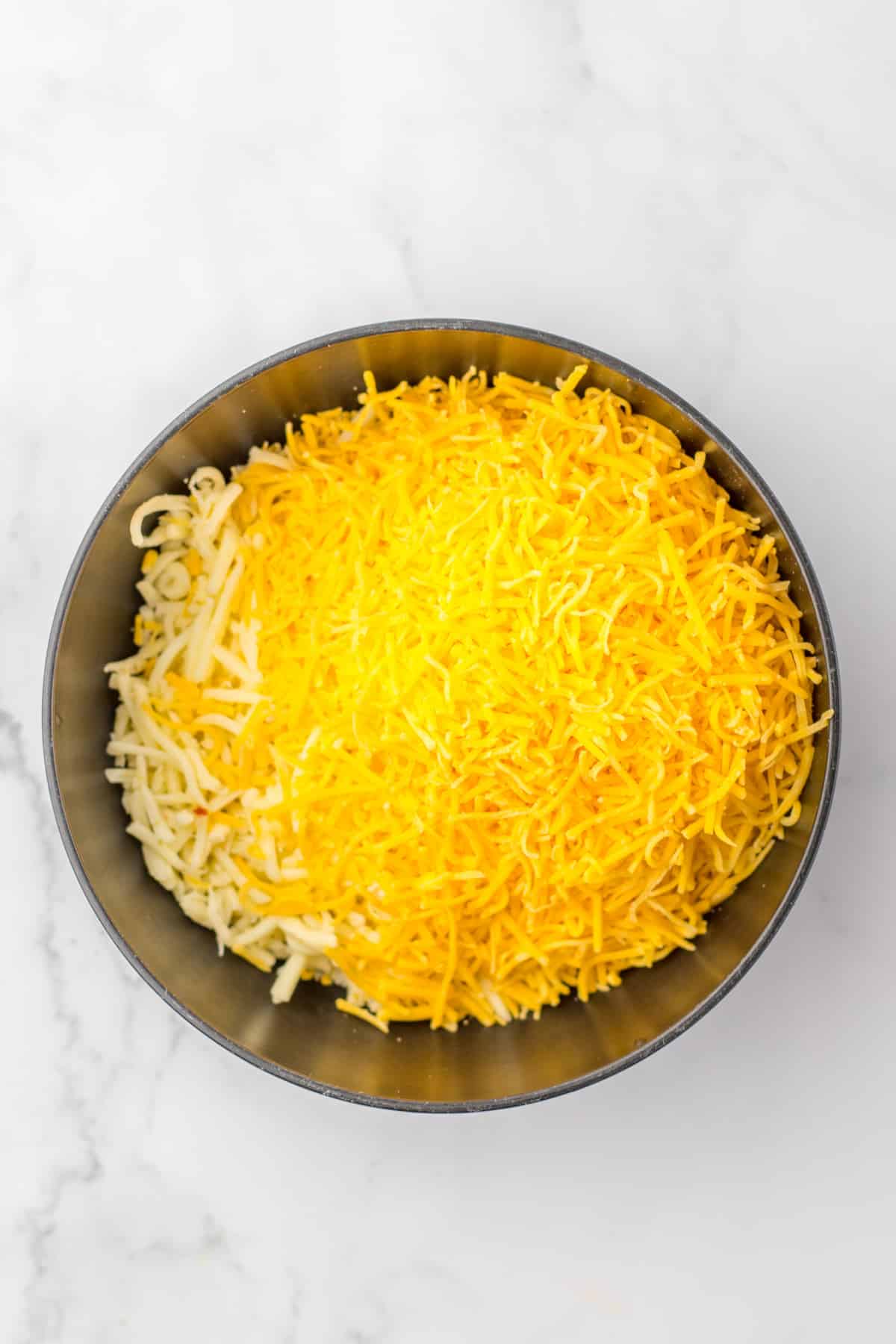 cheese, cooked sausage, and hashbrowns in a mixing bowl.