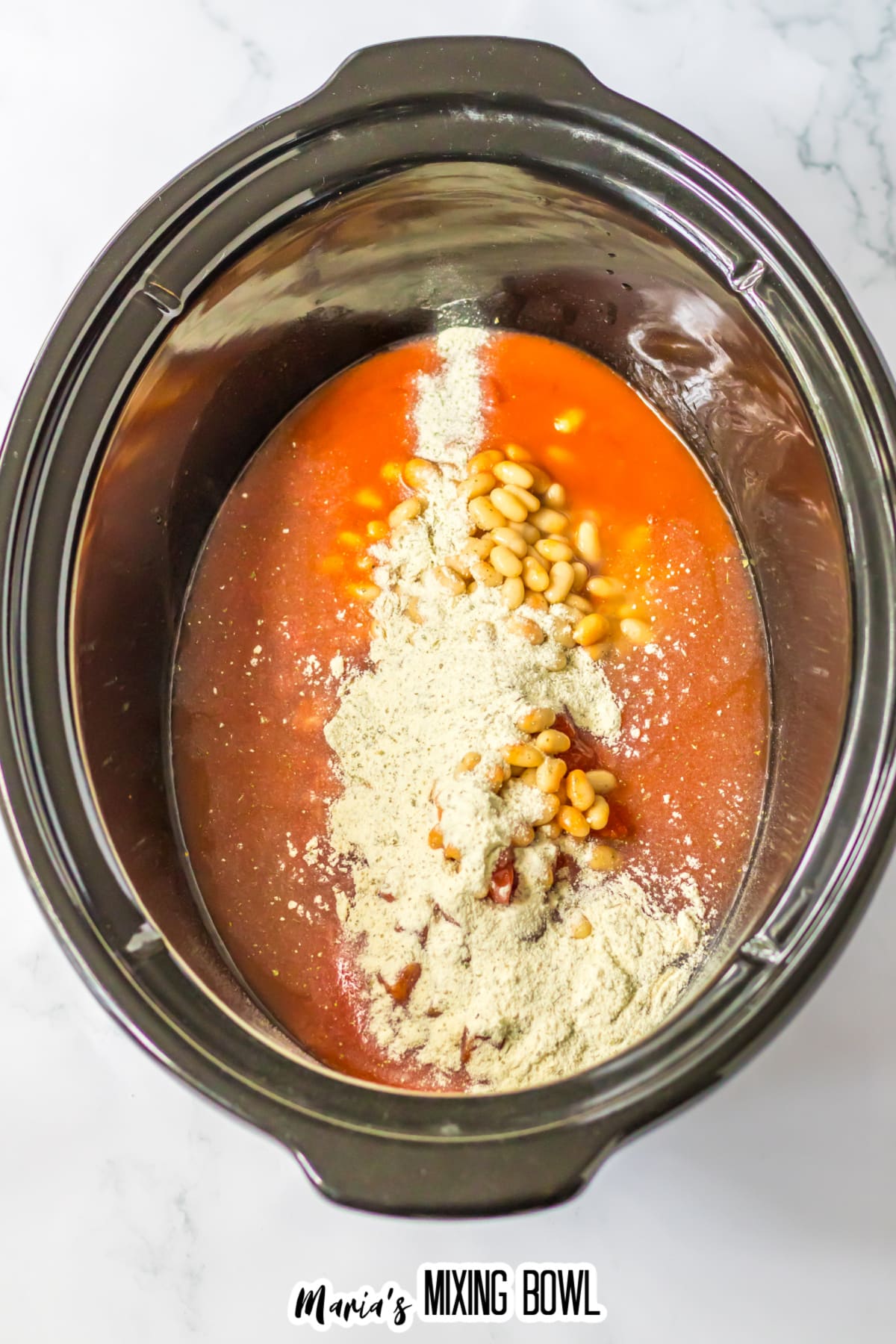 seasonings, beans, raw chicken, and buffalo sauce, in a slow cooker.