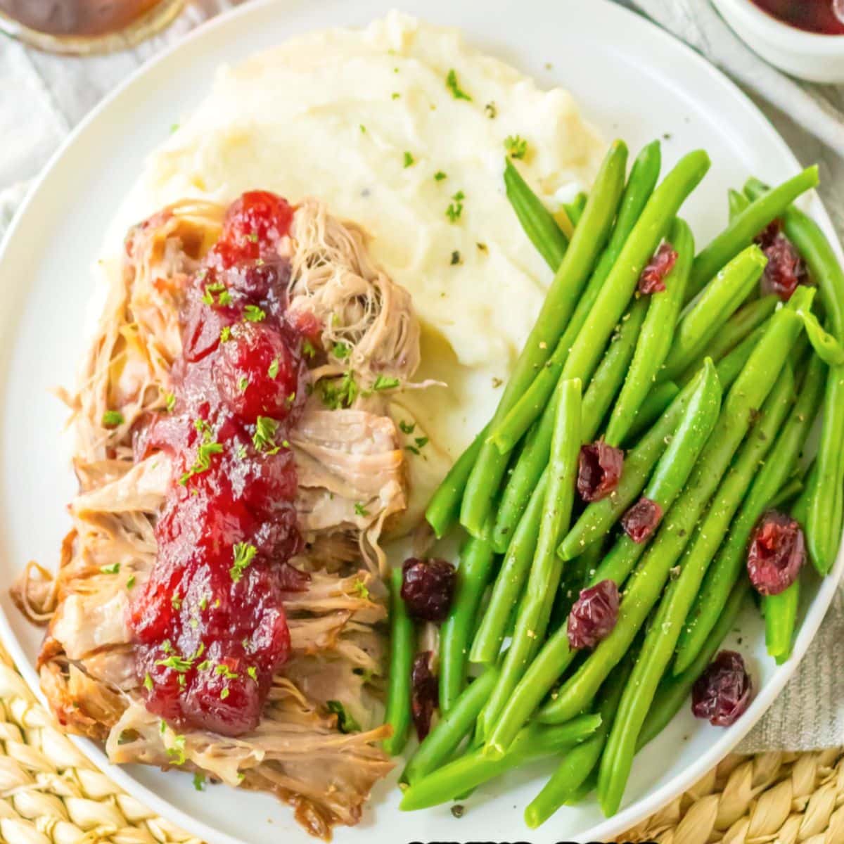 cranberry roast pork loin on a plate with mashed potatoes and green beans.