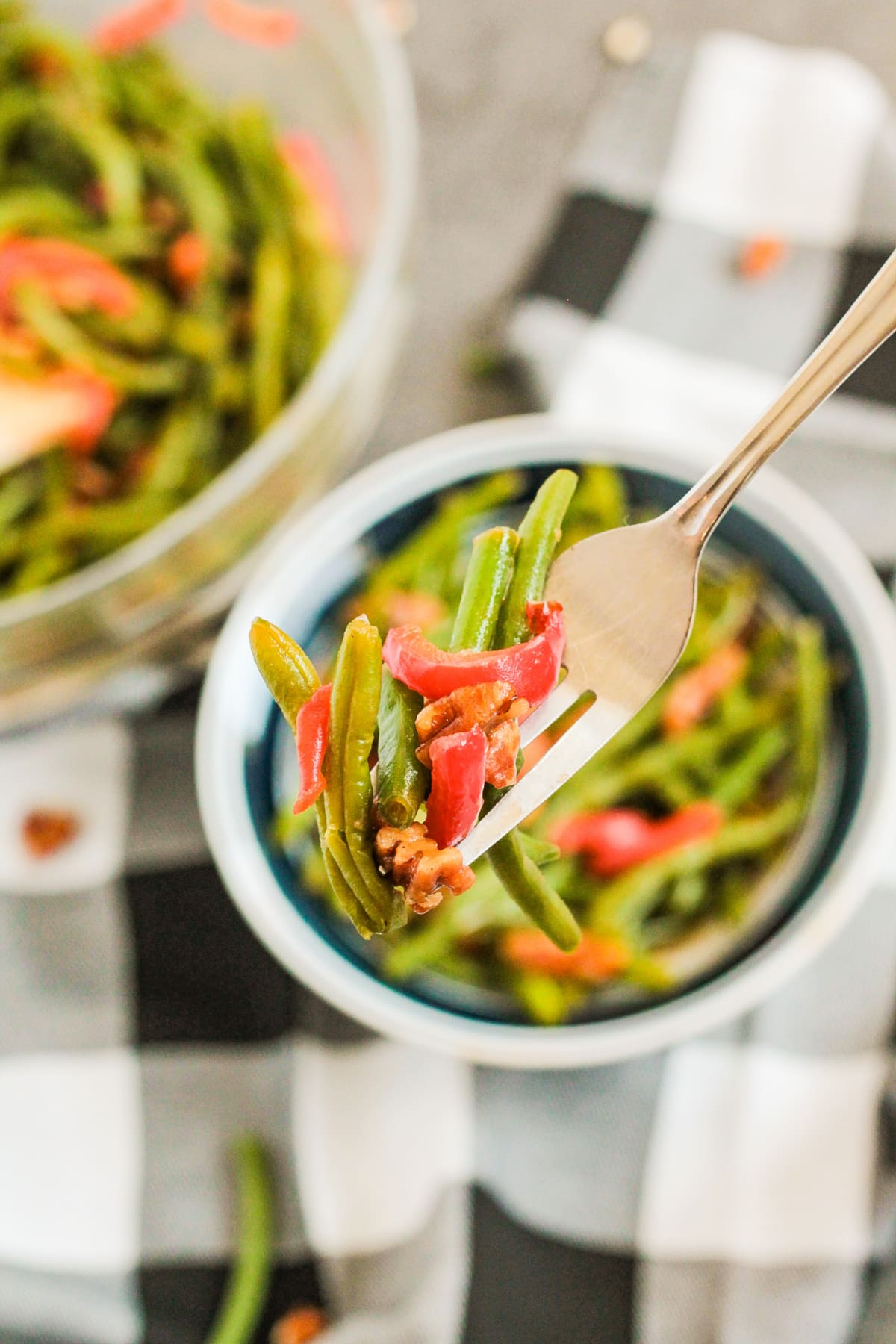 bite of spicy green beans on a fork held in the air.