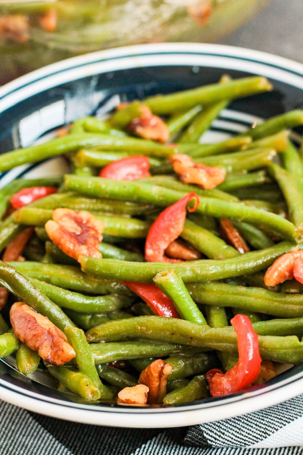 bowl of spicy green beans with red peppers and pecans.