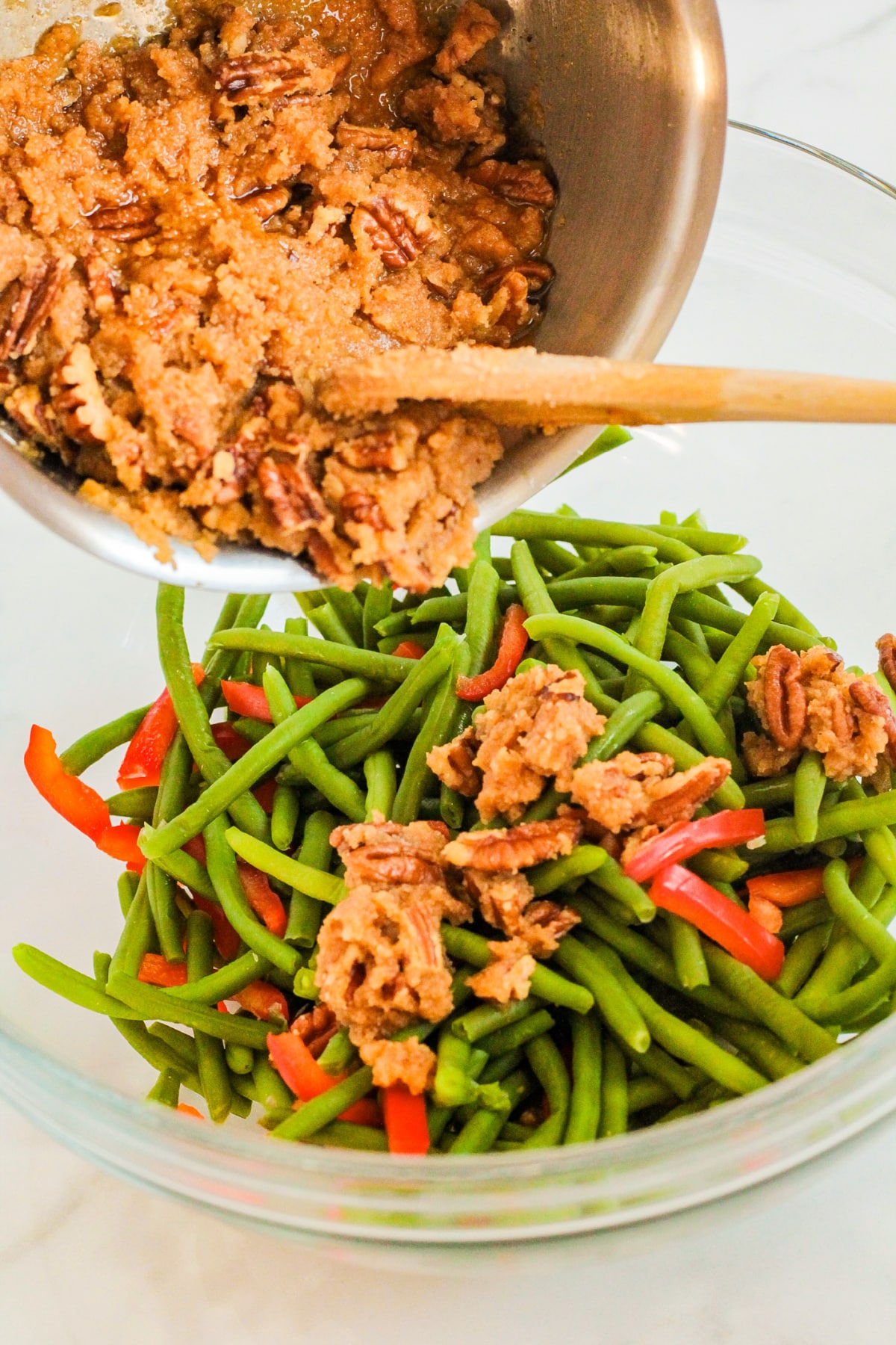 spicy pecan sauce being tossed in green beans and bell peppers.