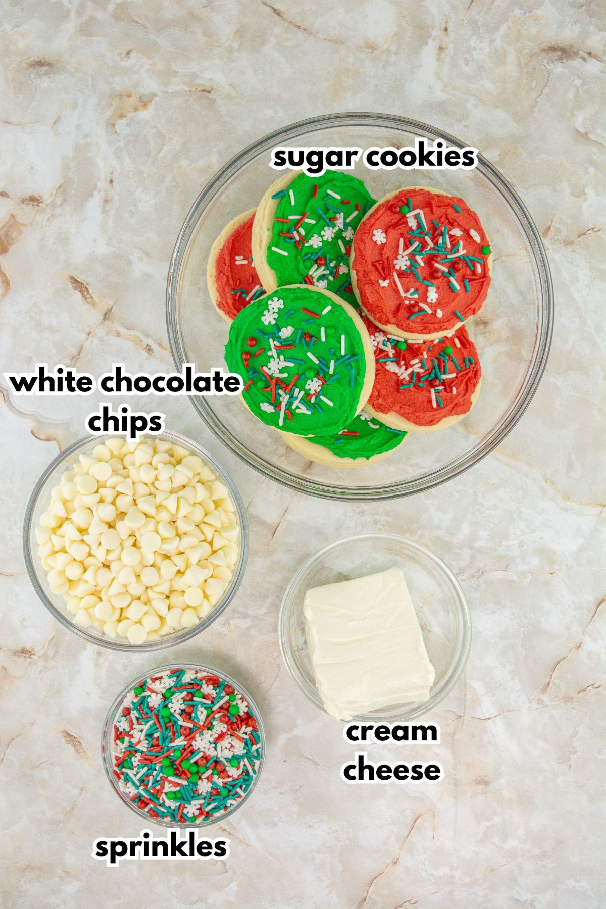 bowls of frosted cookies, white chocolate chips, sprinkles, and cream cheese.