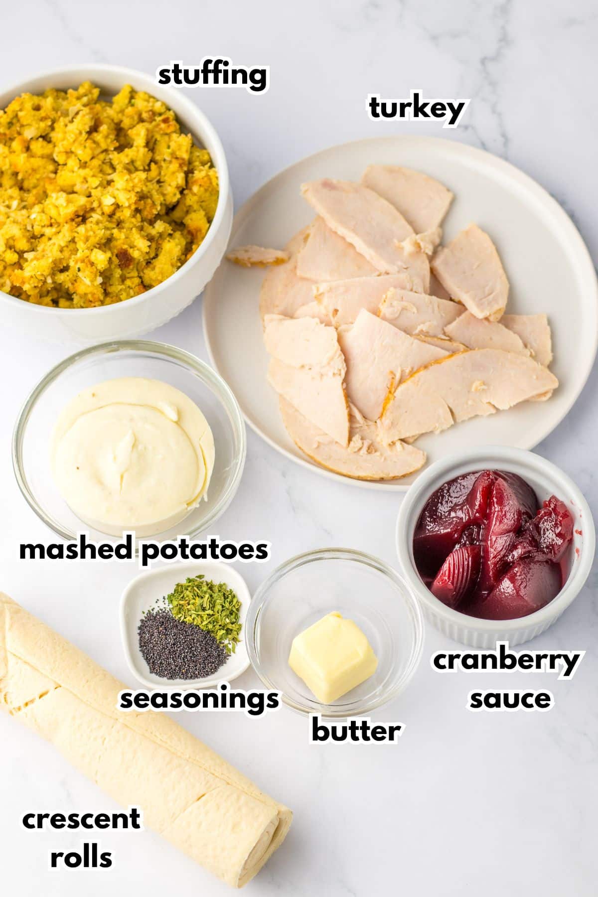 bowls of stuffing, turkey, mashed potatoes, cranberry sauce, seasonings, butter, and crescent rolls.
