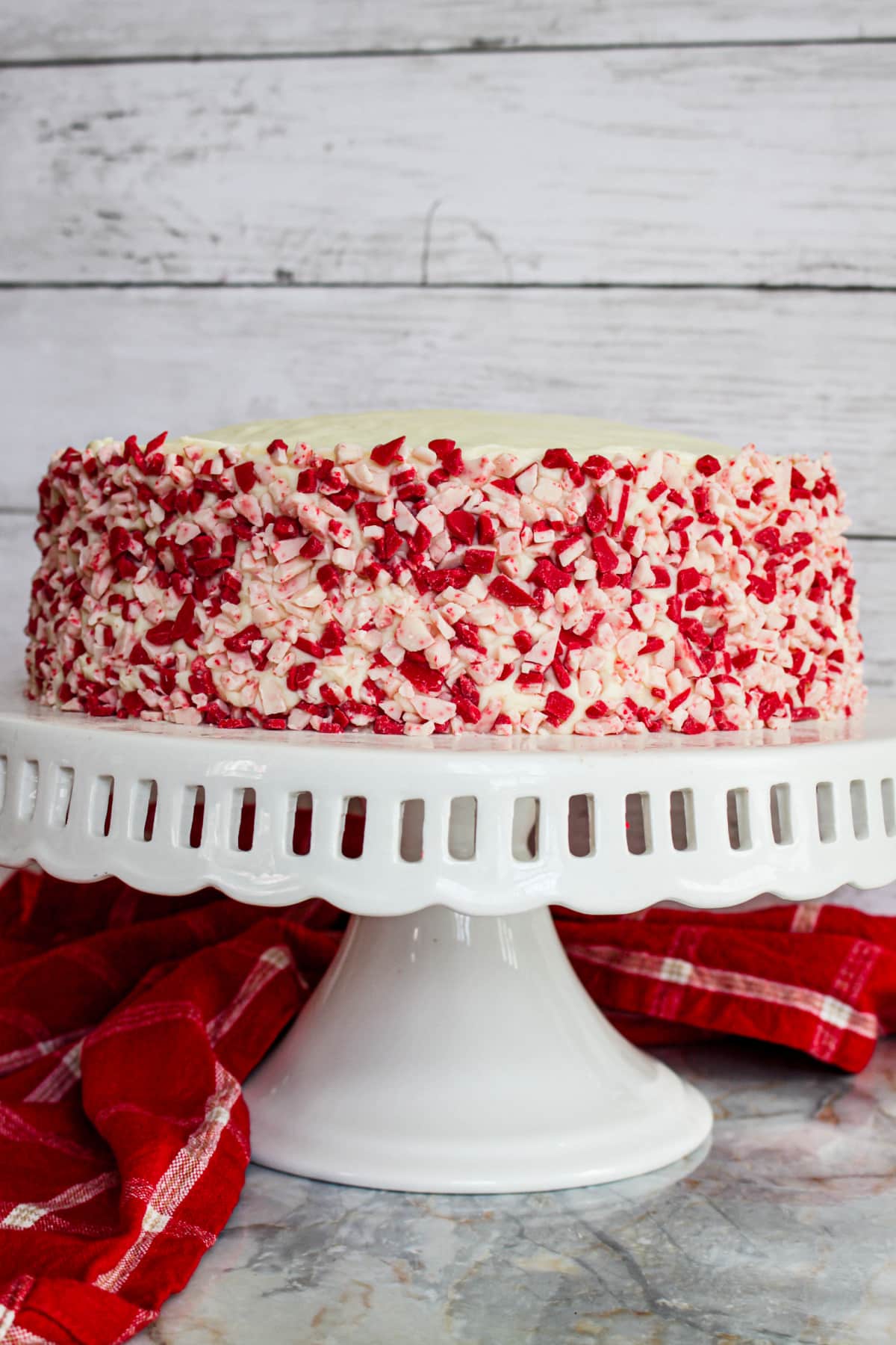 uncut white chocolate peppermint cake on a cake stand.