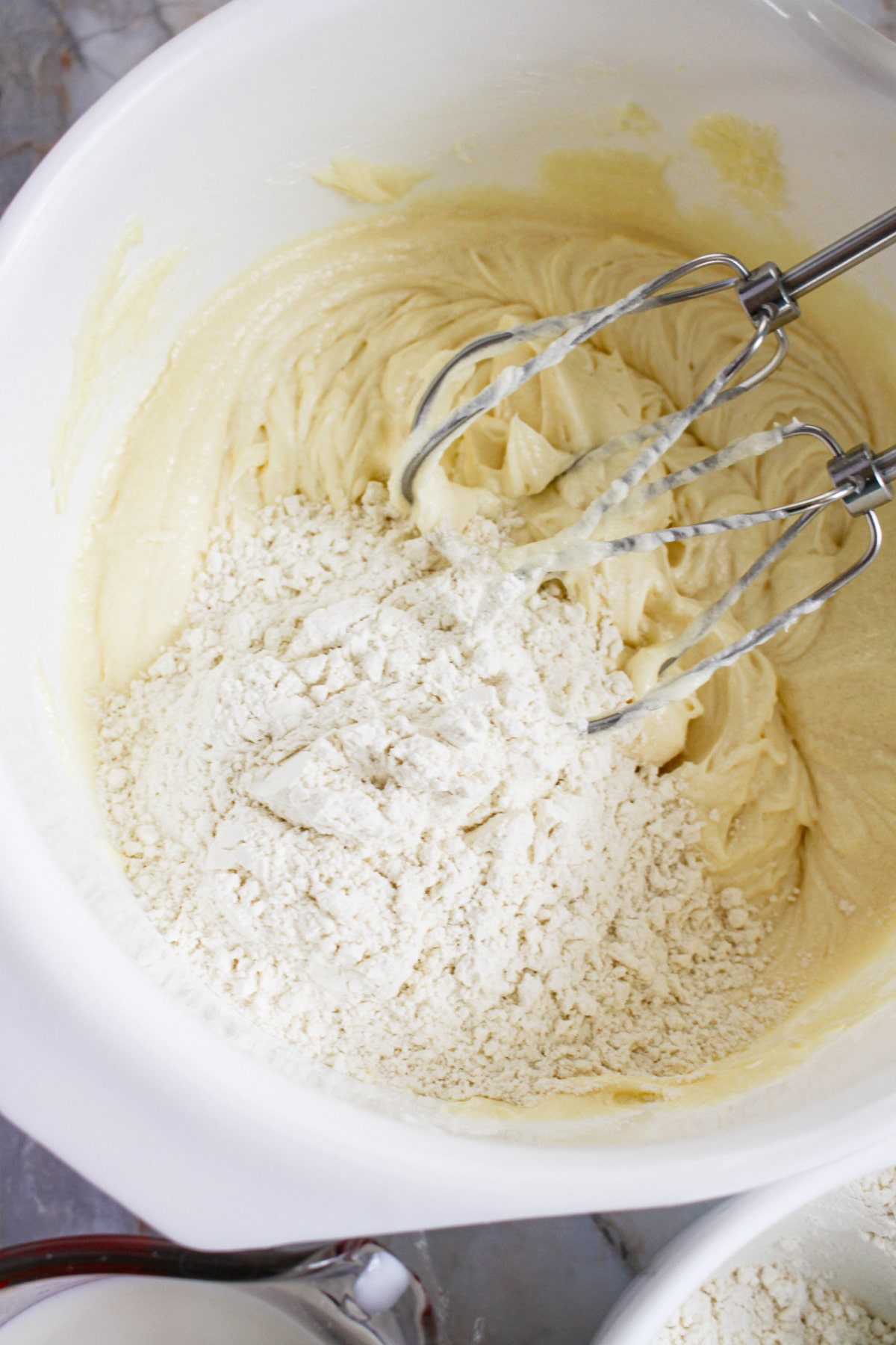 cake batter being mixed with a hand mixer in a mixing bowl.