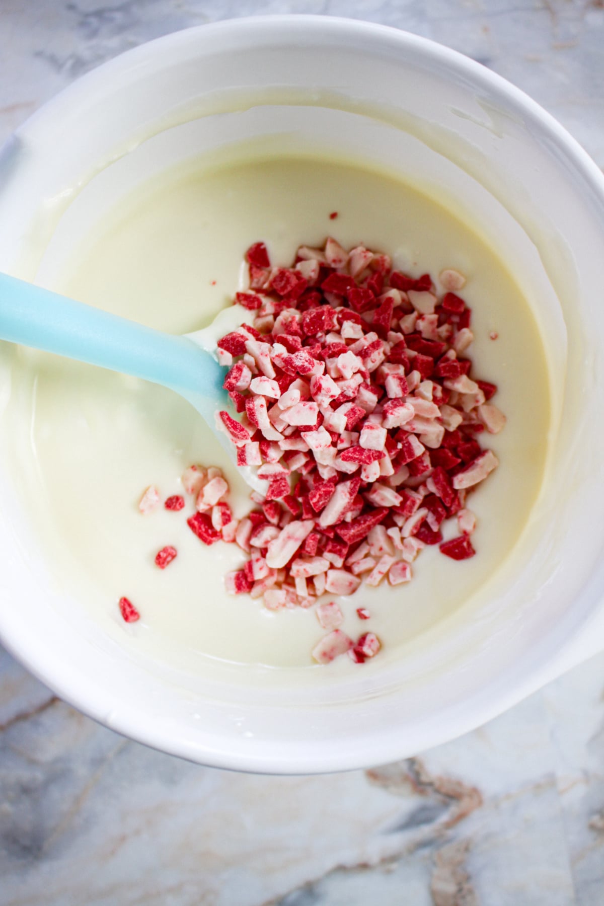 peppermint chips being added to melted white chocolate.