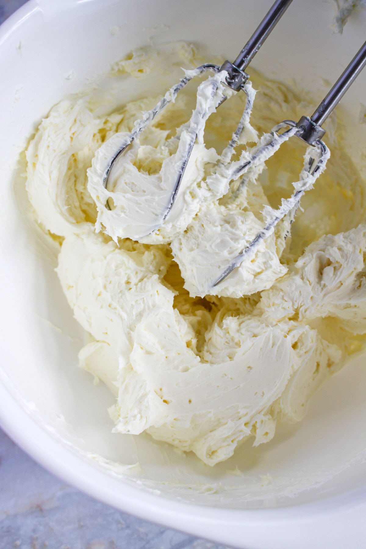 peppermint frosting being mixed with a hand mixer in a large bowl.