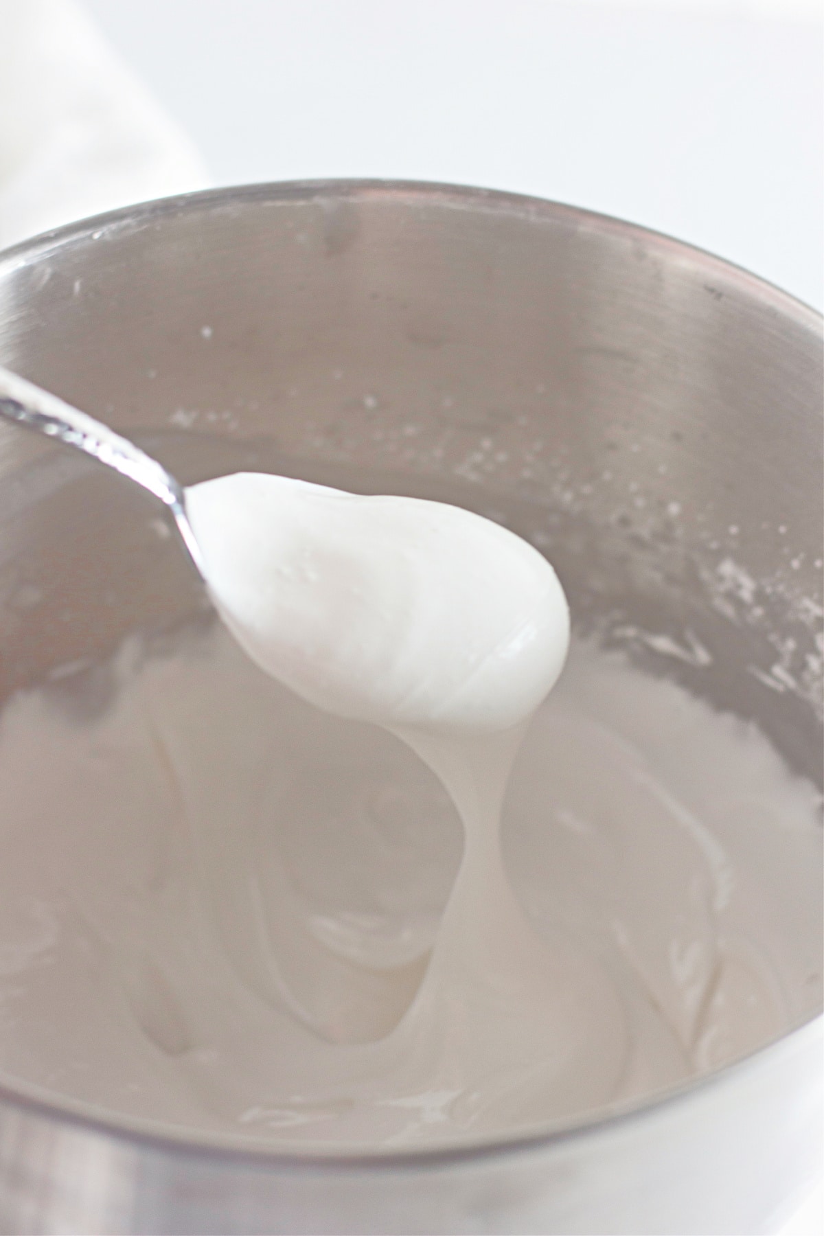 royal frosting being mixed in a stainless steel mixing bowl.