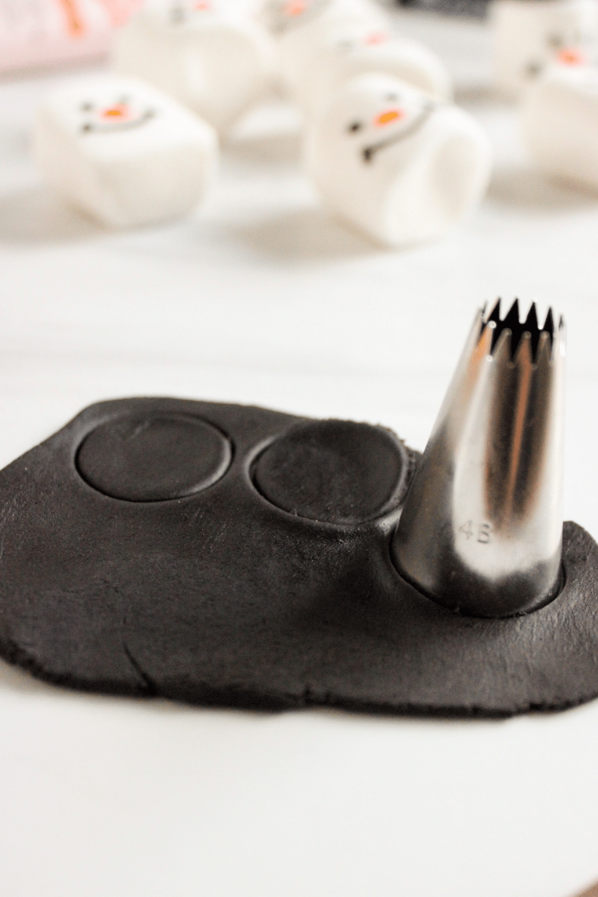 hats being cut of black fondant with the tip to a piping bag.