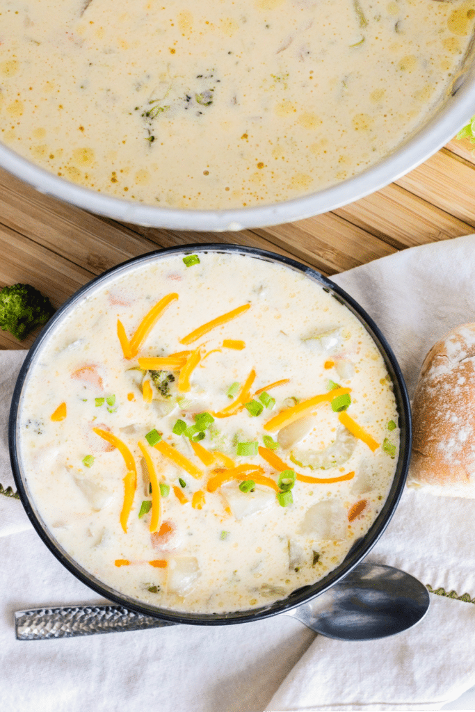 bowl filled with cheesy potato soup and topped with shredded cheese and sliced green onions.