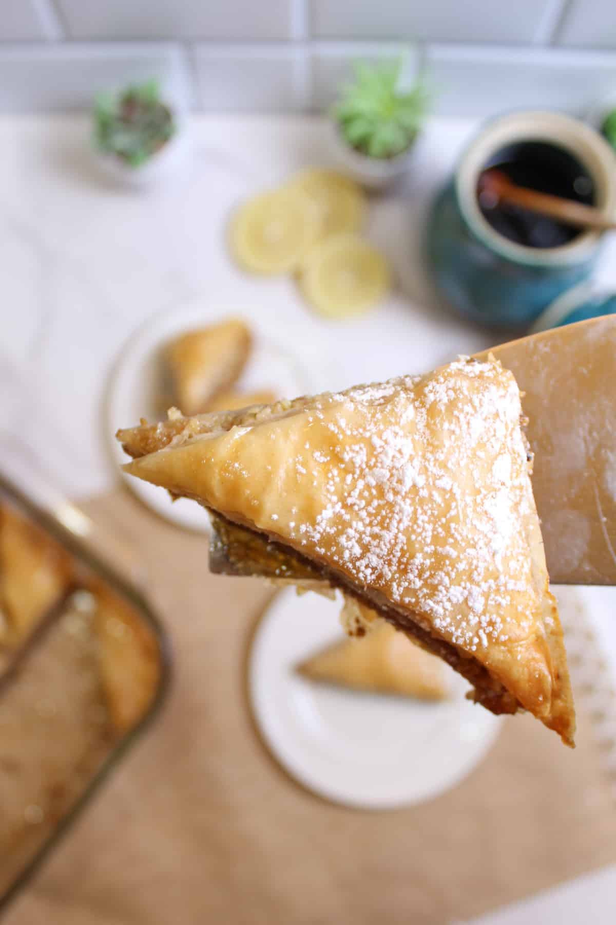 slice of baklava held on a spatula in the air.
