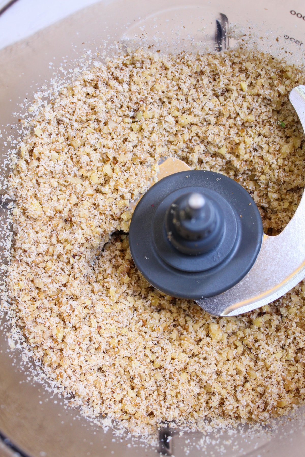 pecans being crushed into a food processor.