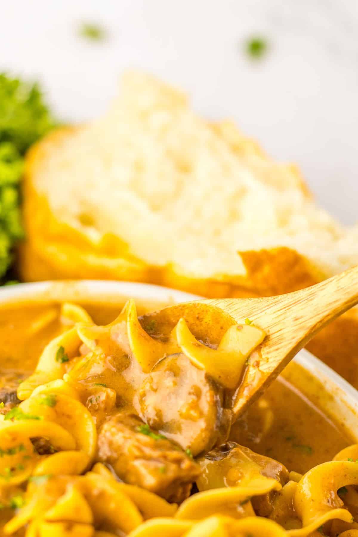 wooden spoon full of a bite of beef mushroom soup.