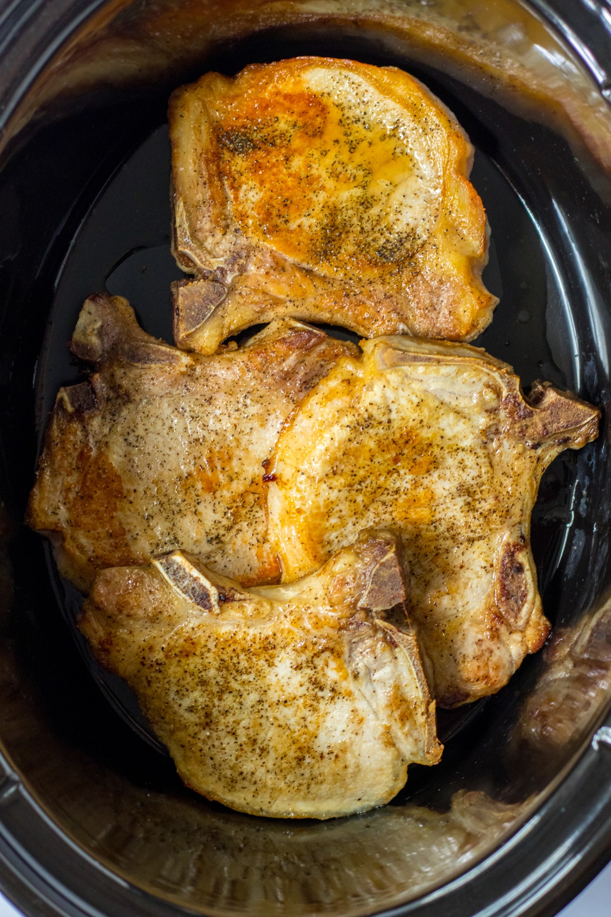 seasoned and seared pork chops in a slow cooker.