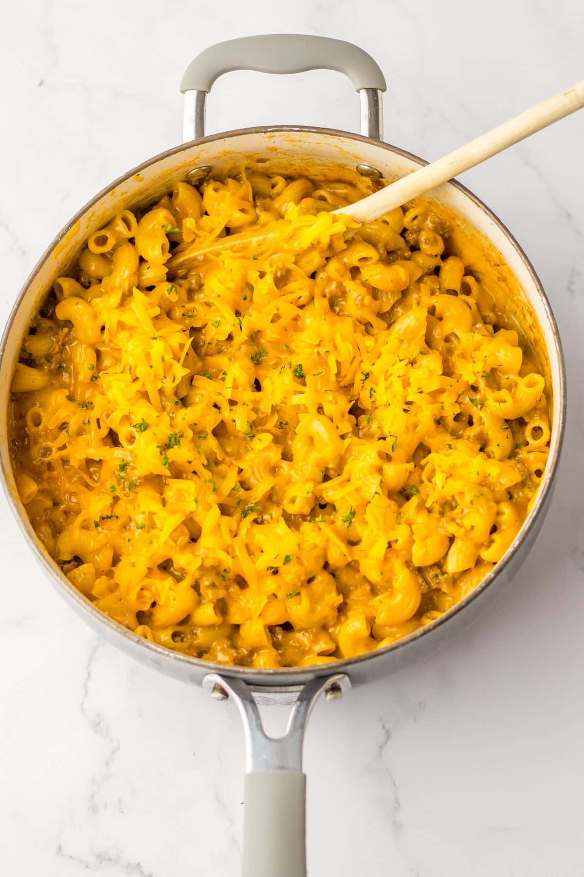 one pot cheeseburger pasta in a skillet with shredded cheese melted on top.