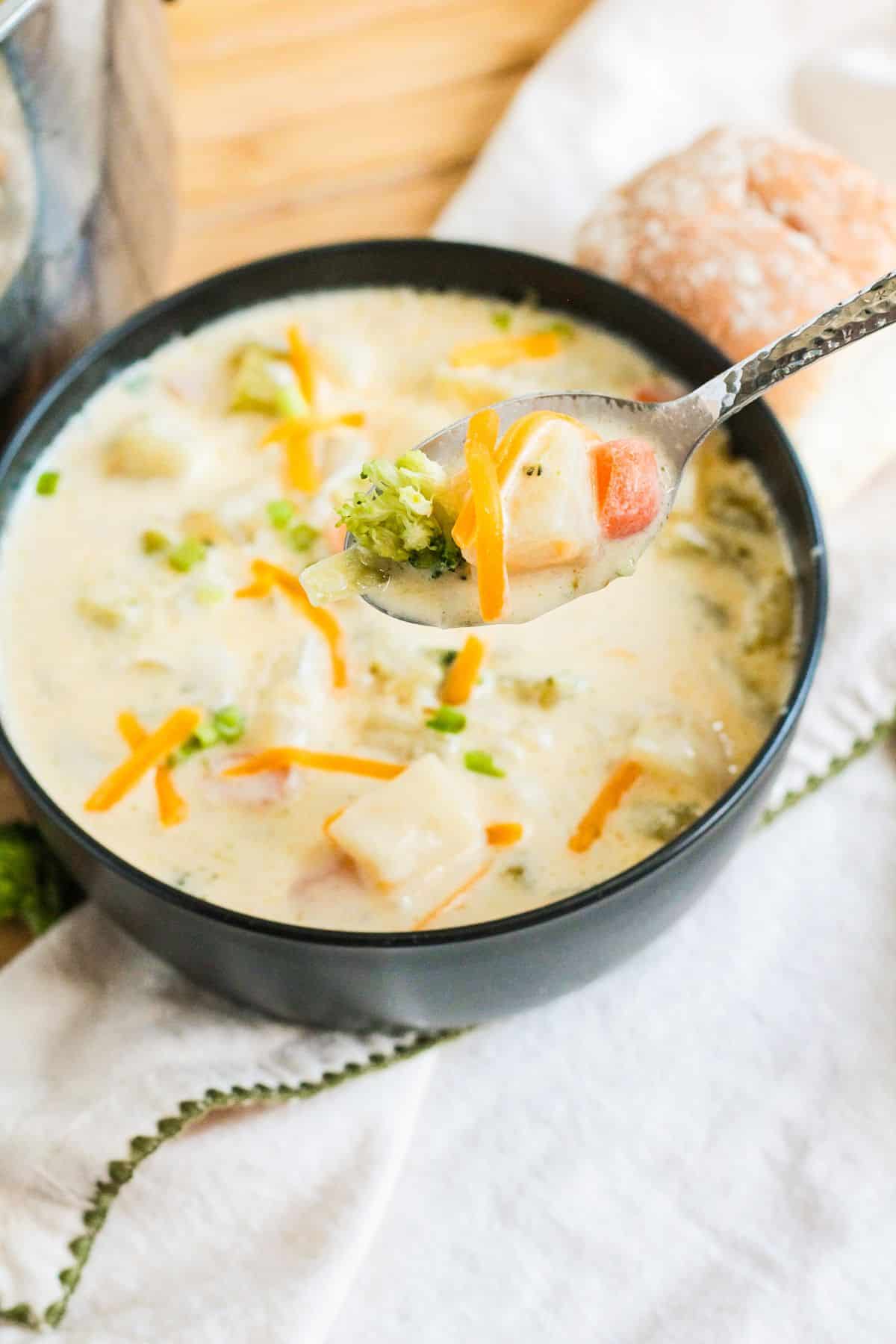bowl filled with cheesy potato soup and topped with shredded cheese and sliced green onions.