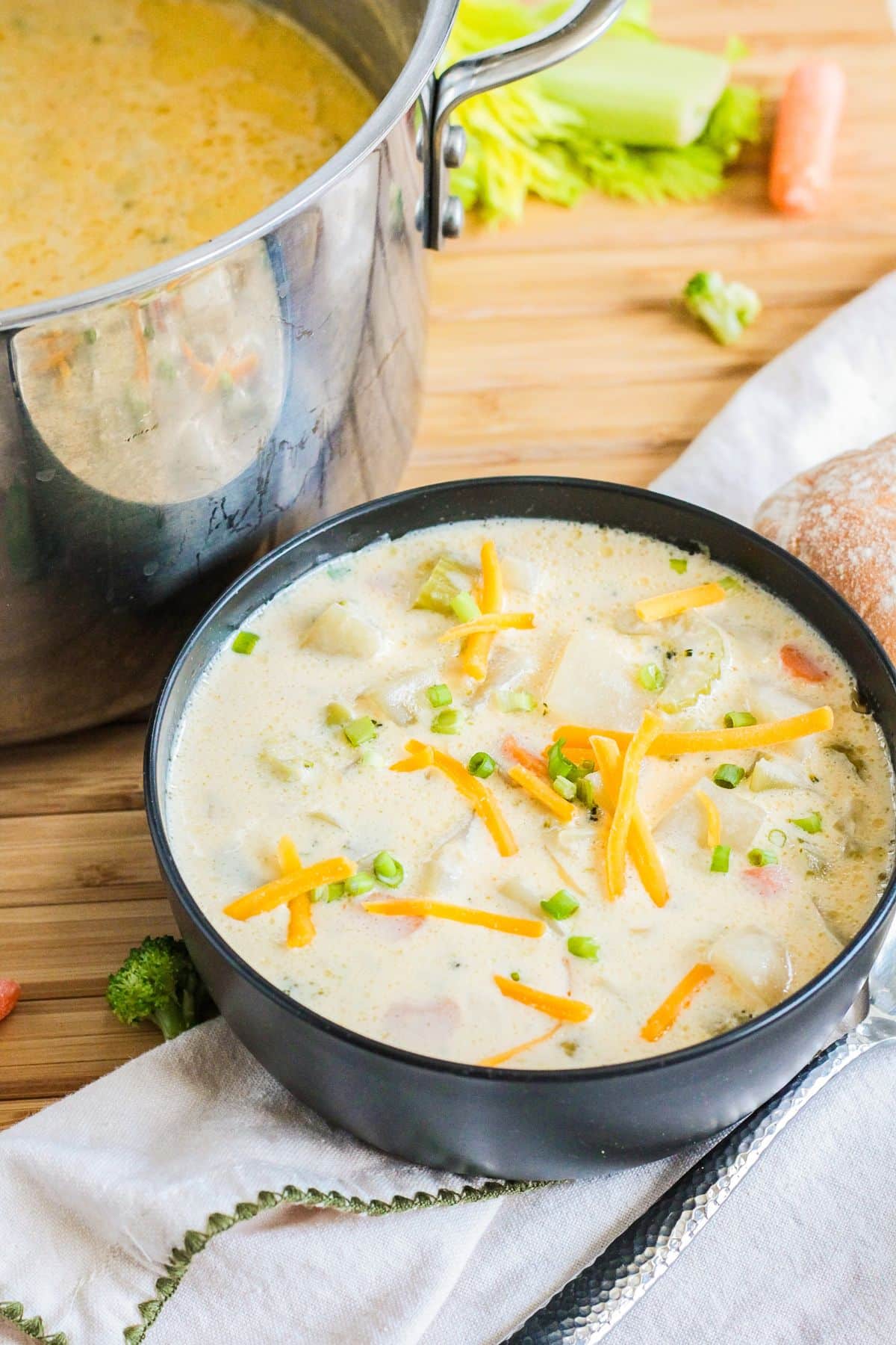 bowl filled with cheesy potato soup and topped with shredded cheese and sliced green onions.