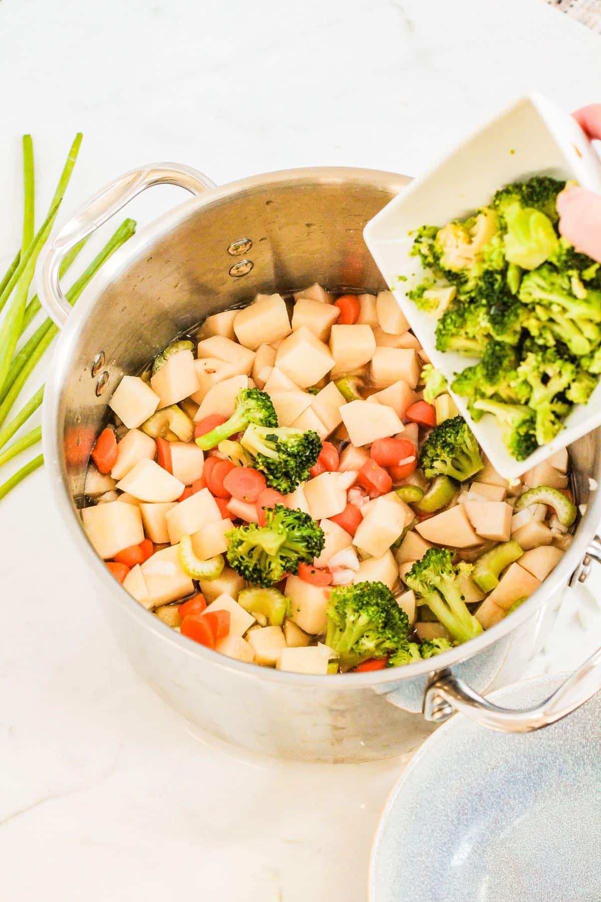 vegetables and potatoes being added to a large pot.