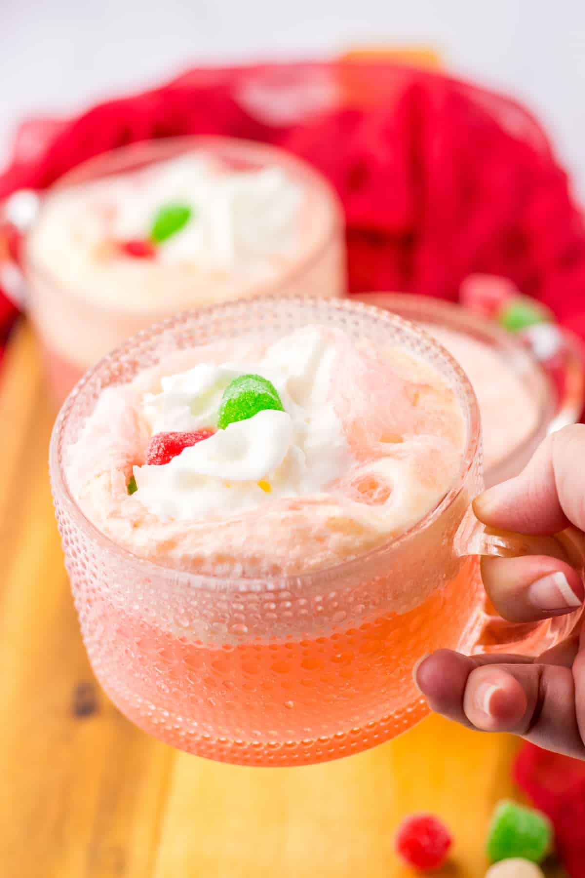 glass mug full of cherry punch and topped with whipped cream and gumdrops.
