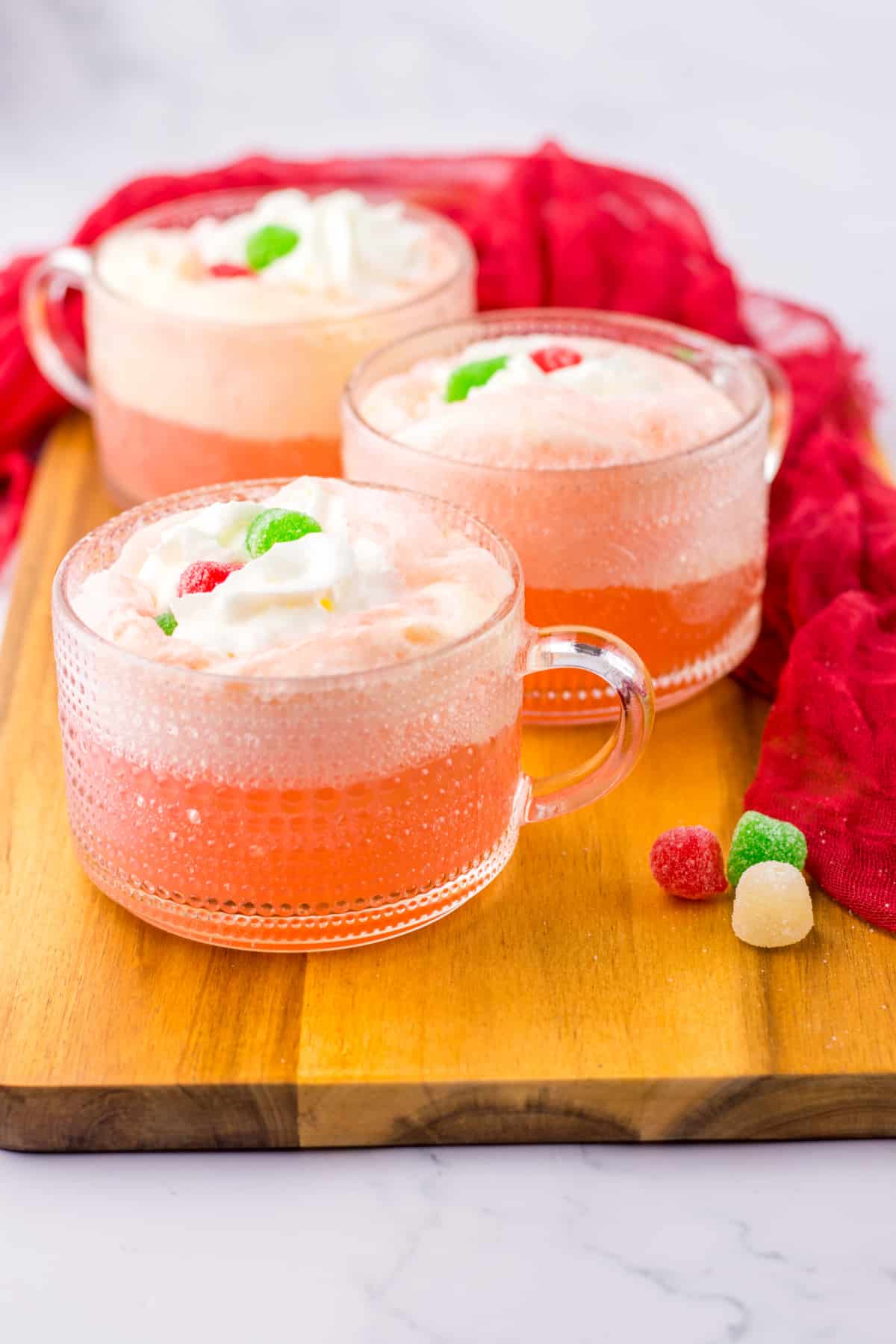 glass mug full of cherry punch and topped with whipped cream and gumdrops.