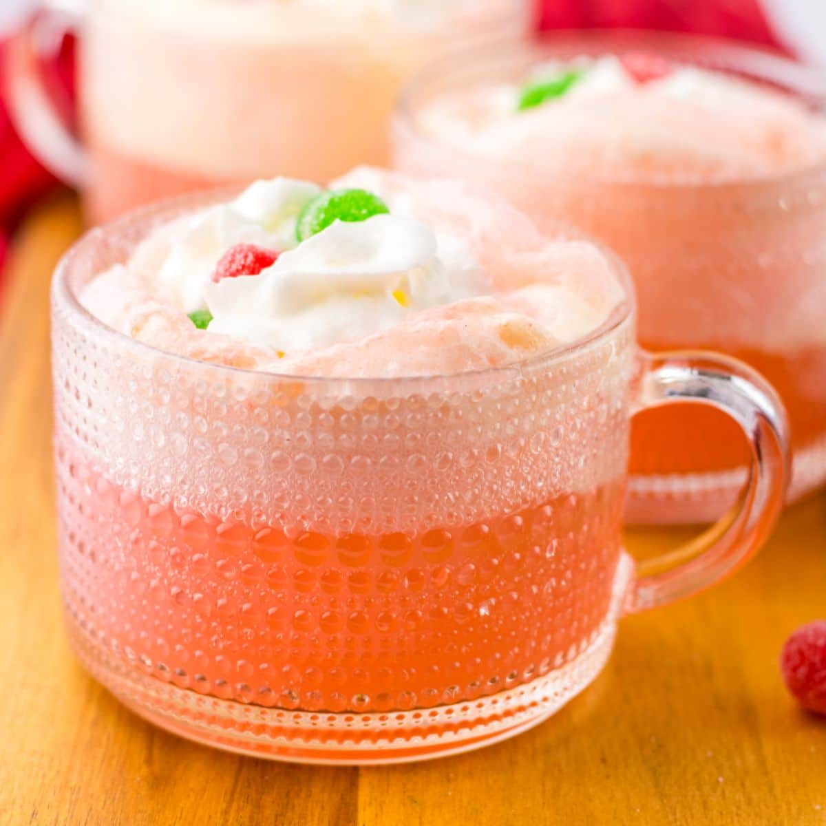 glass mug full of cherry punch and topped with whipped cream and gumdrops.