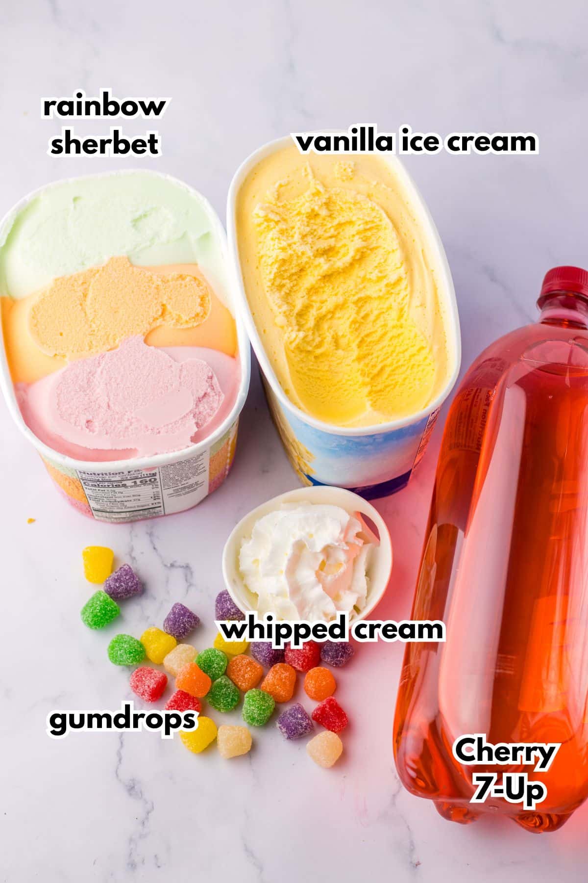 cartons of rainbow sherbet, vanilla ice cream, bottle of cherry 7up, bowl of whipped cream and gumdrops.