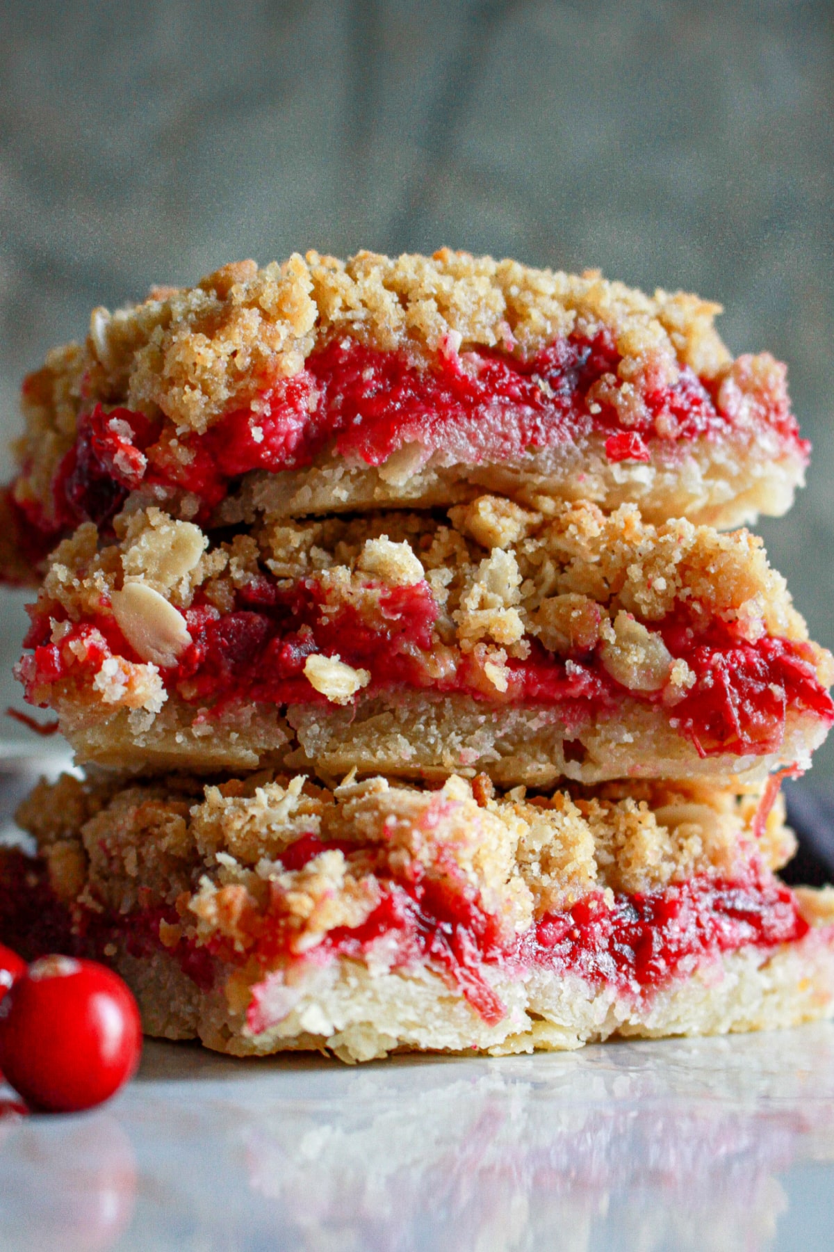 three cranberry crumble bars stacked on top of one another.