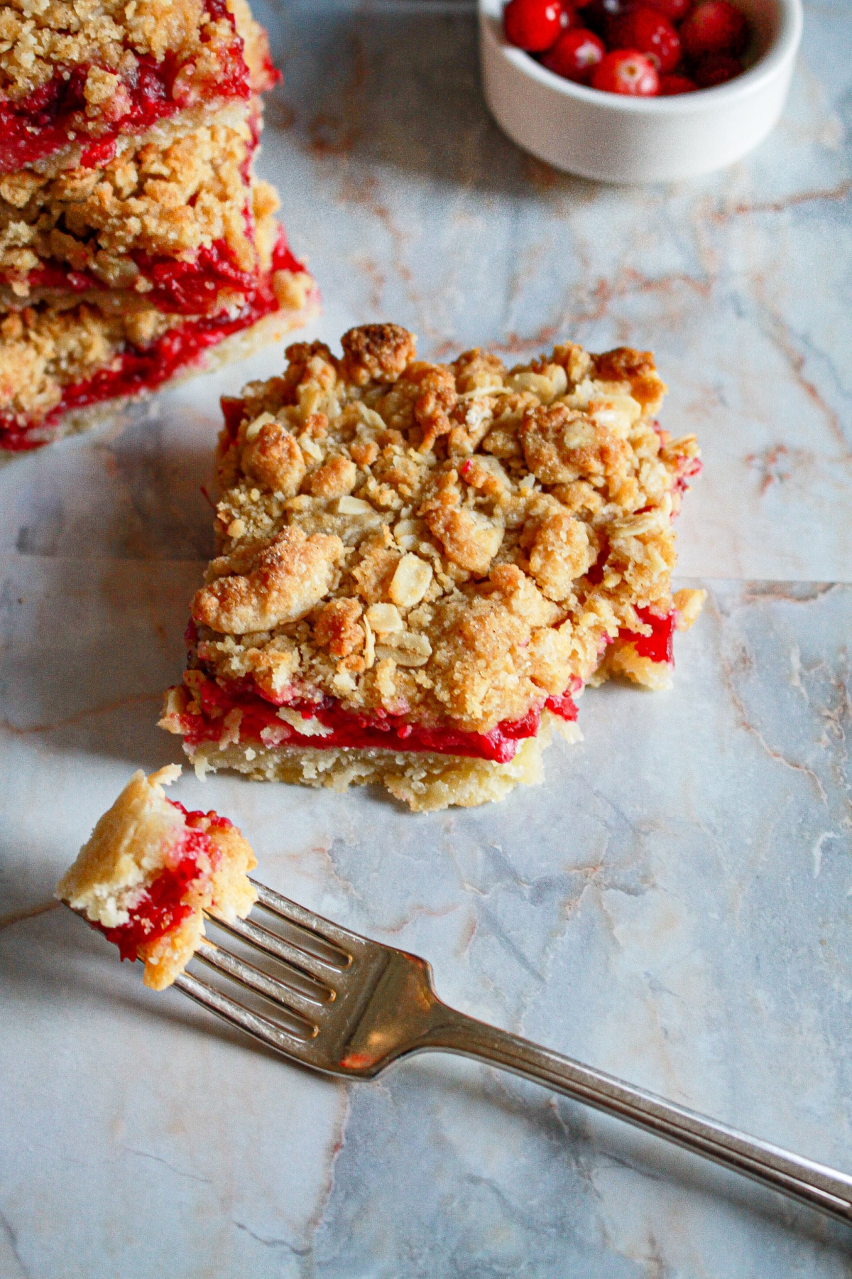 slice of cranberry crumble bars with a bite missing.