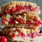 three cranberry crumble bars stacked on top of one another.