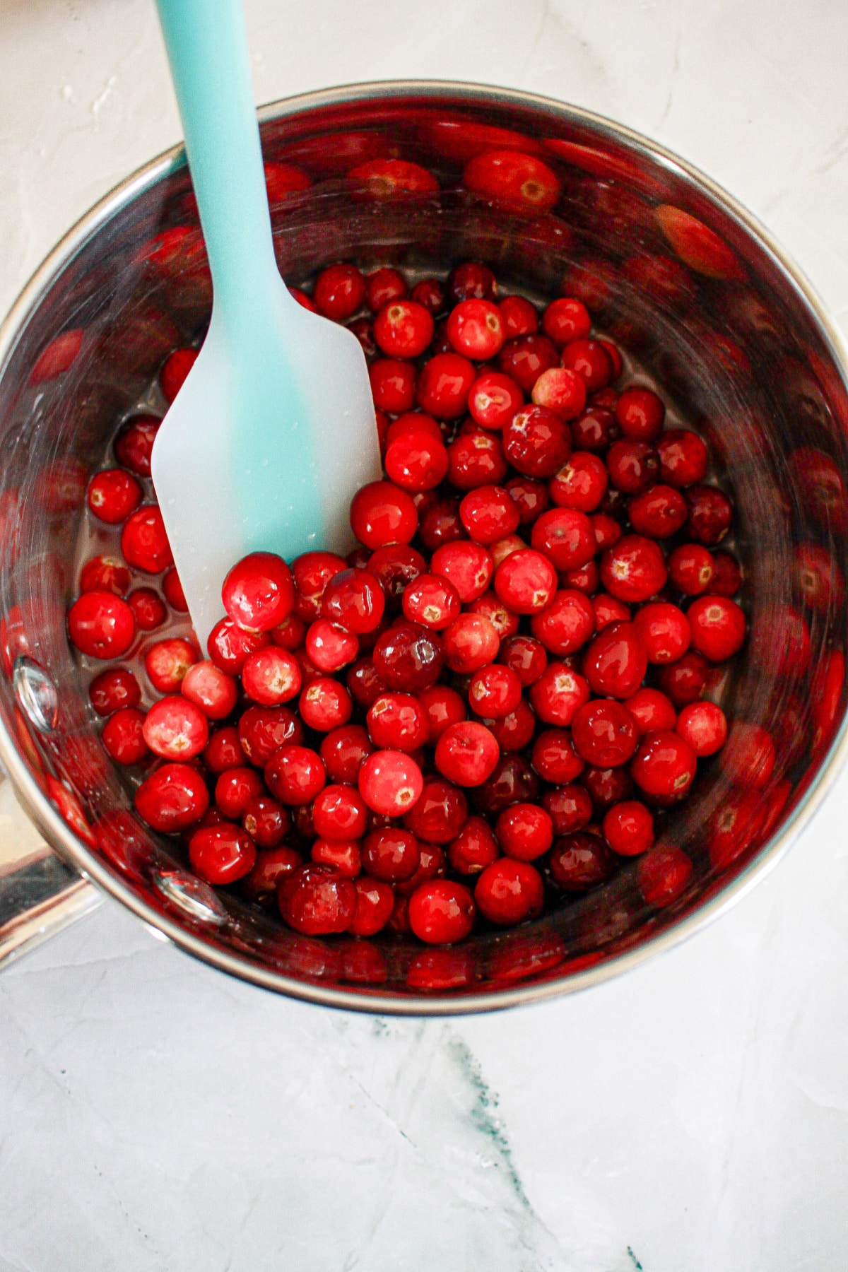 cranberries being cooked in a saucepan.