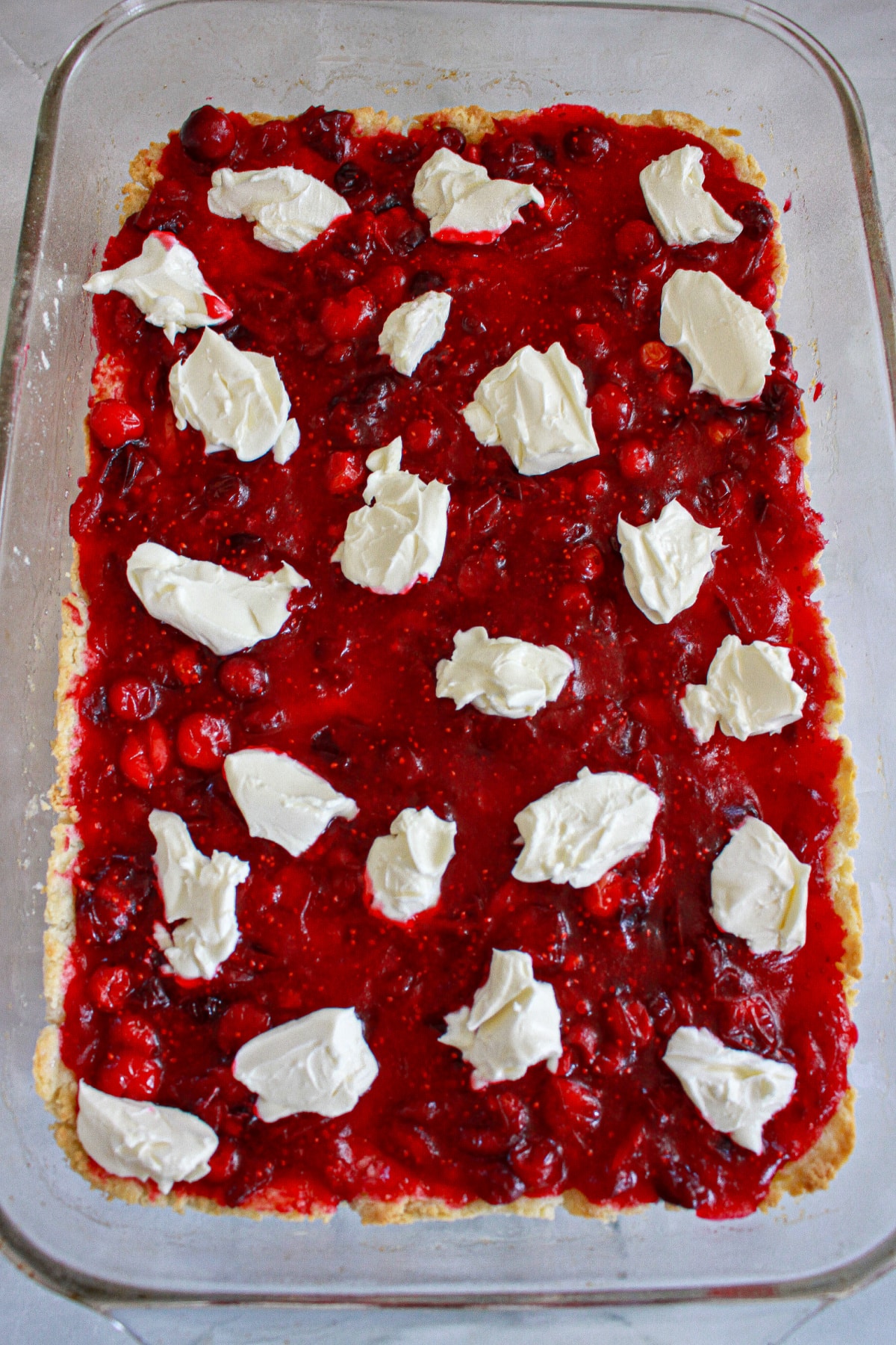 cream cheese being added to the top of cranberry filling.