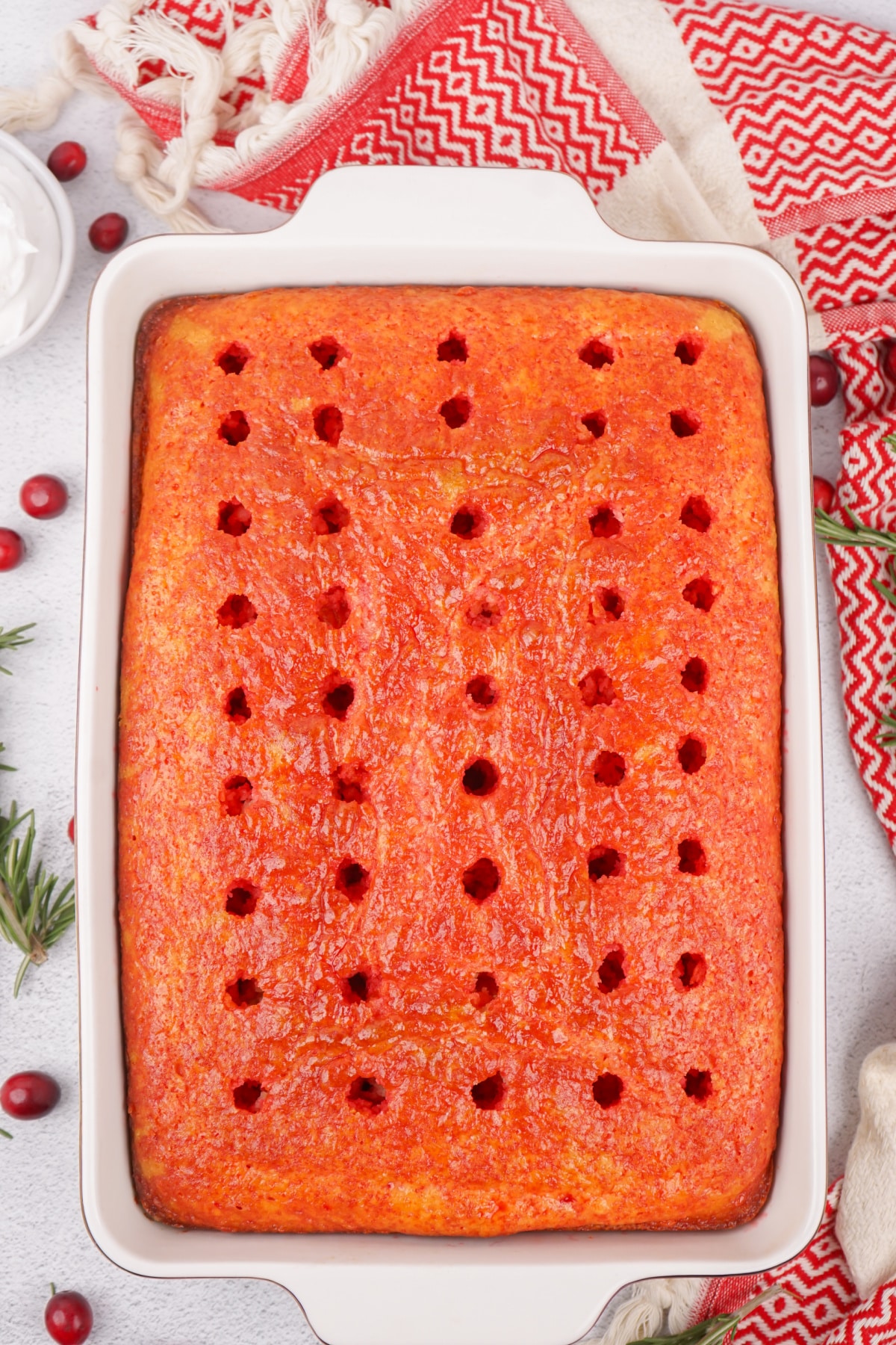raspberry jello poured over the baked cake in a baking dish.