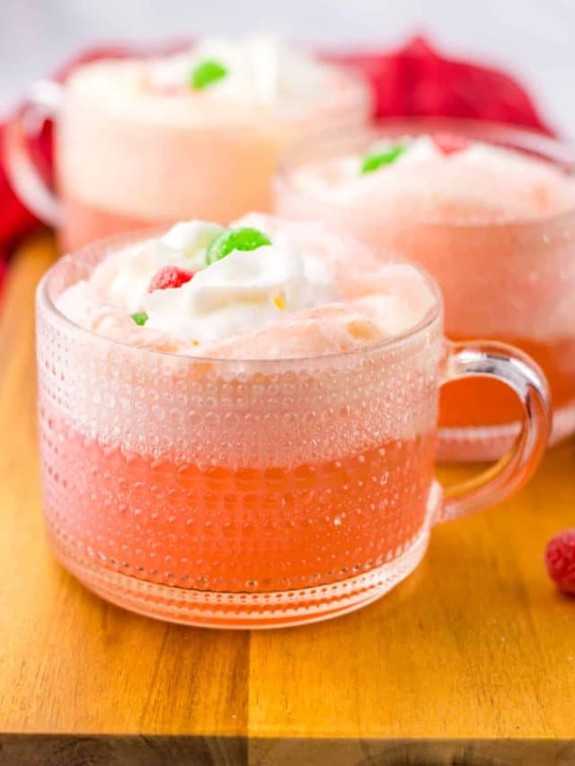 glass mug full of cherry punch and topped with whipped cream and gumdrops.